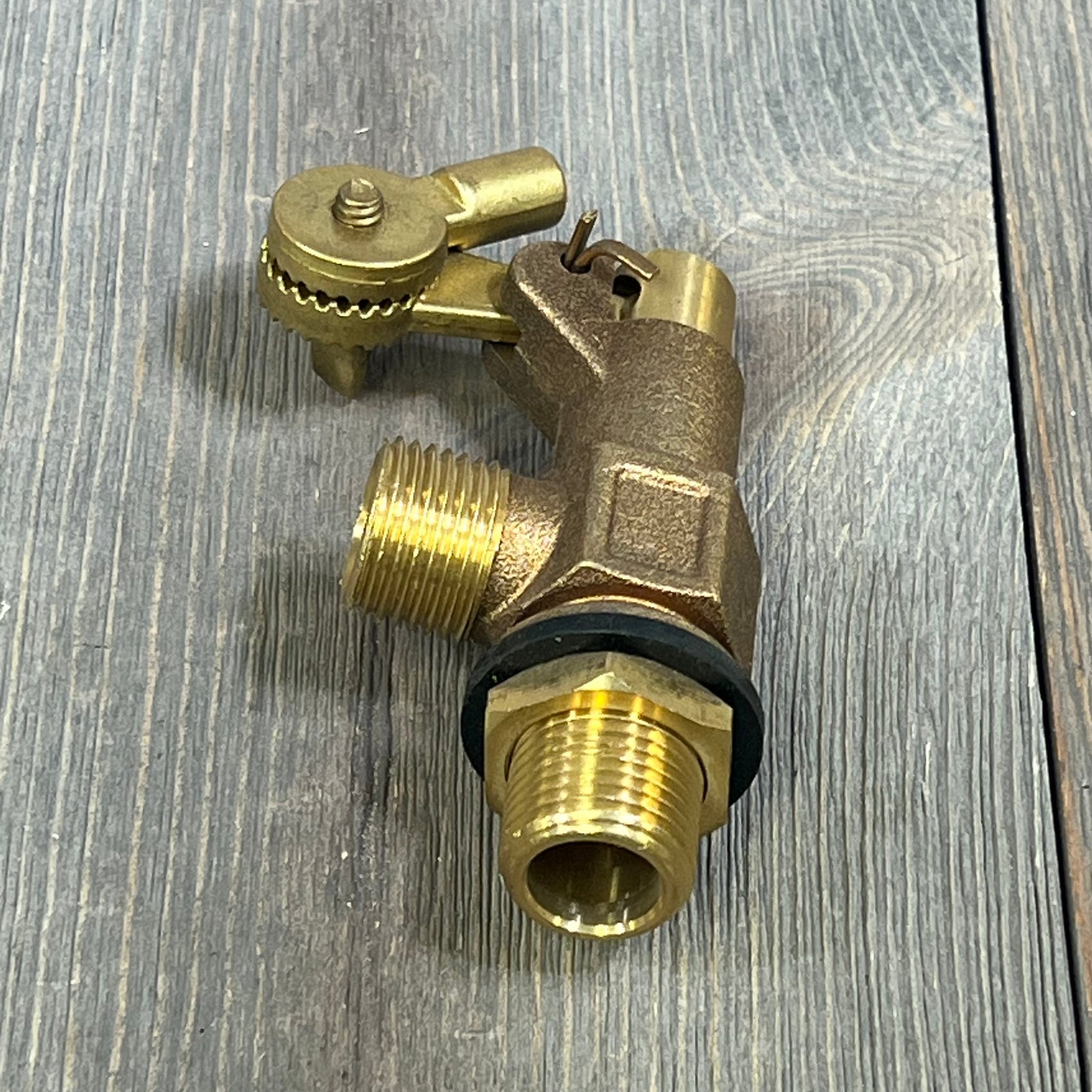 Bronze float valve for water tanks on wooden surface, featuring 1/2 inch inlet and male outlet for efficient water control.