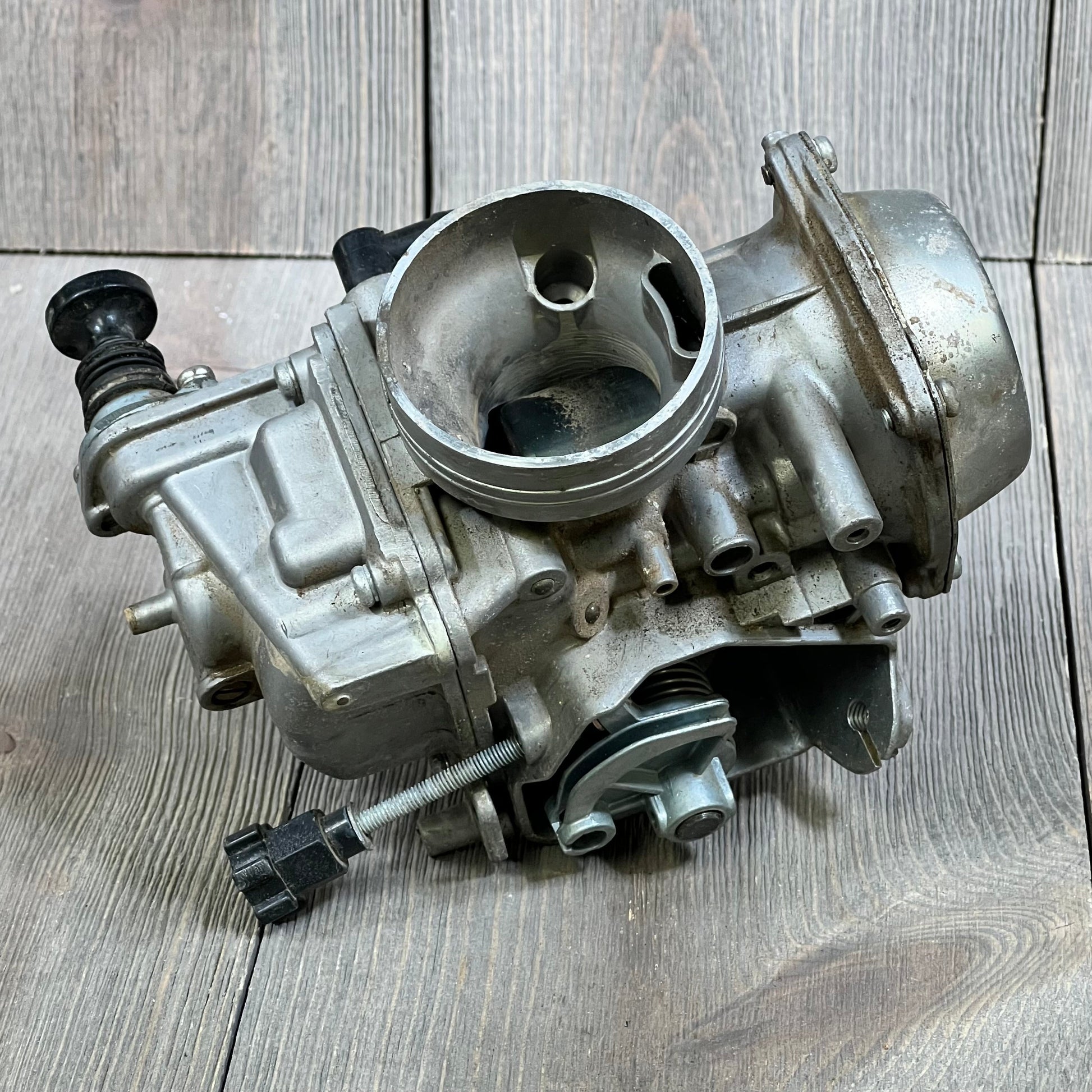 Carbhub TRX300 carburetor for Honda Fourtrax 1988-2000, showcasing detailed side view against a wooden background.