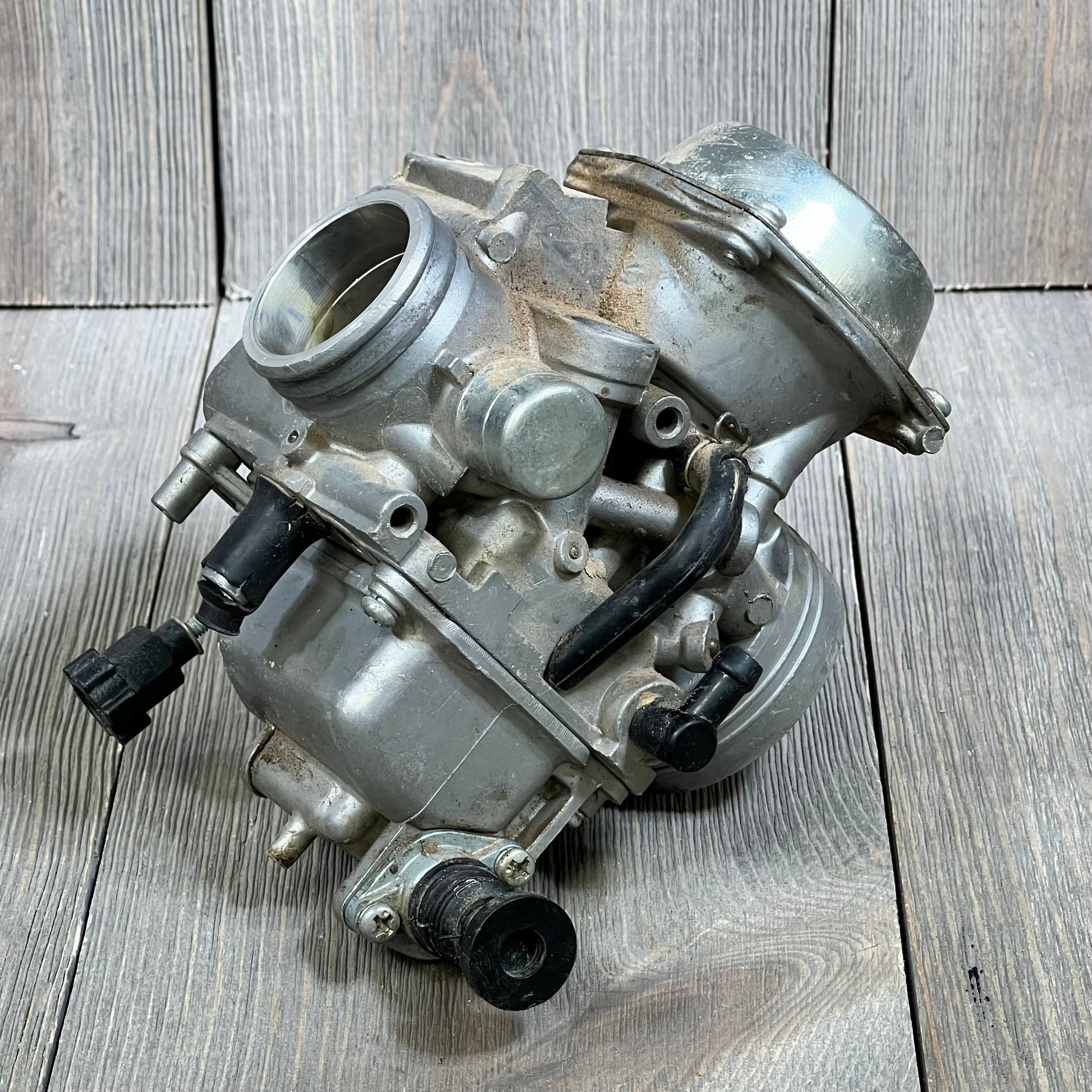 Carbhub TRX300 carburetor for Honda Fourtrax 1988-2000 shown on a wooden surface, highlighting detailed components.