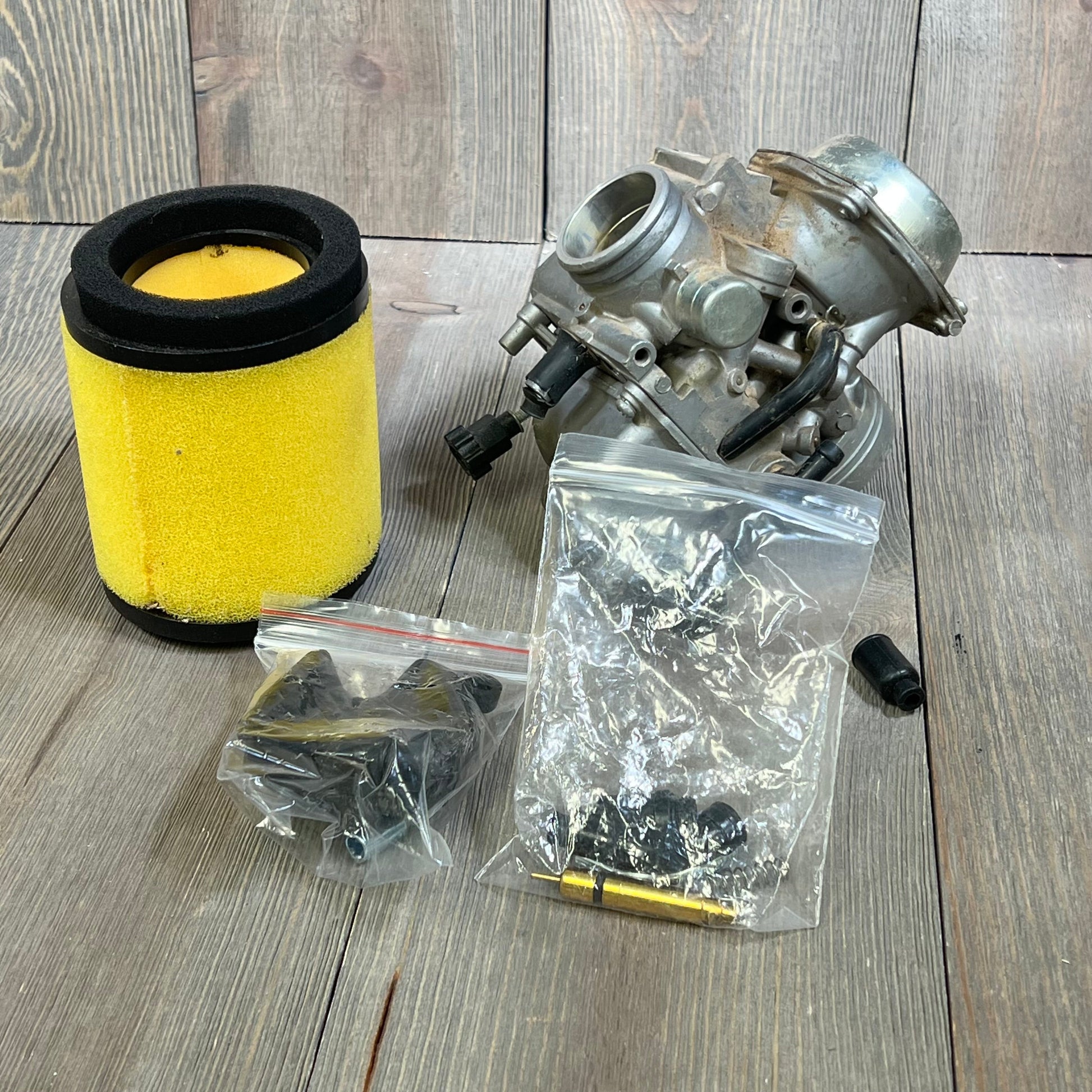 Carbhub TRX300 carburetor set with air filter and accessories for Honda Fourtrax 1988-2000 on wooden surface.