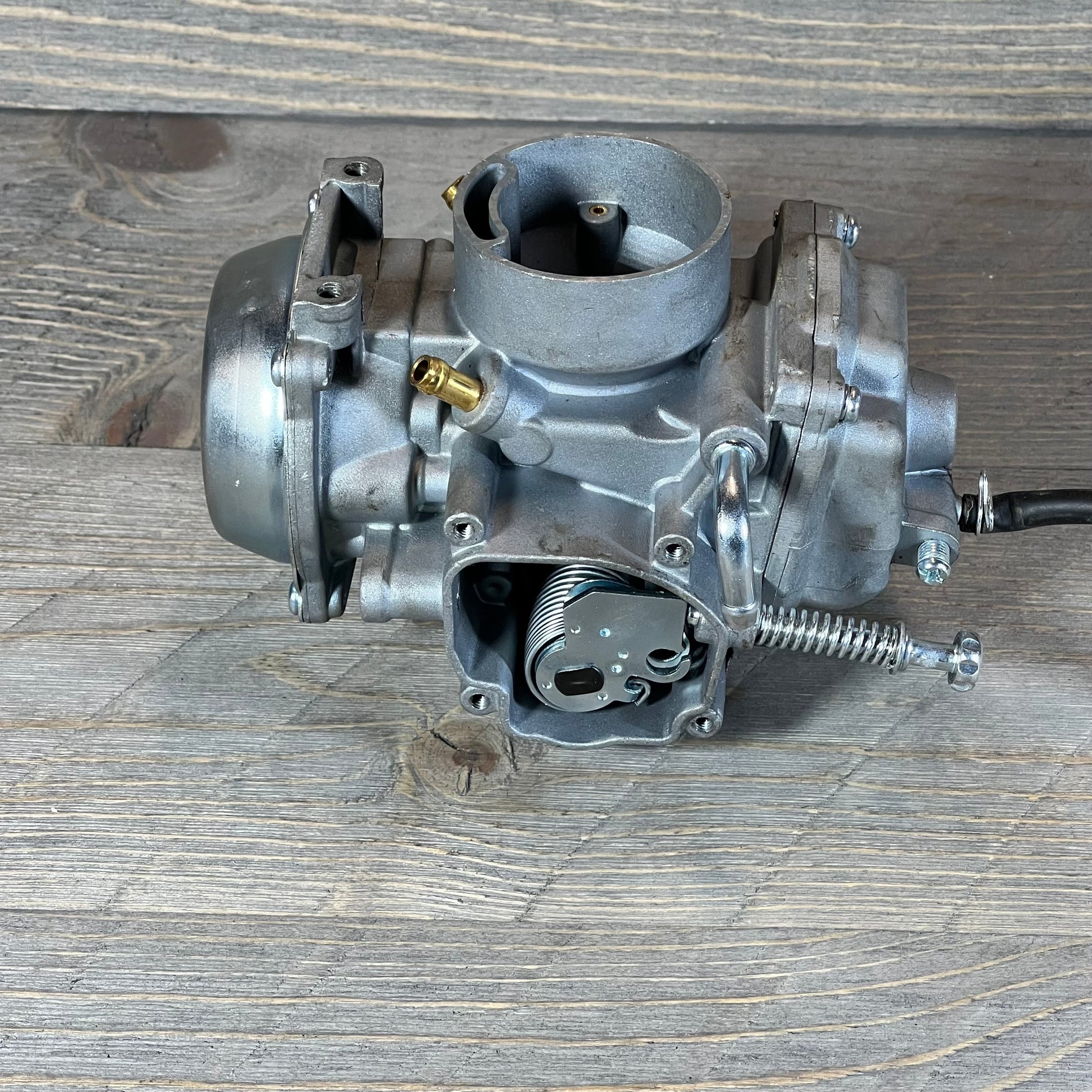 Carburetor ATV replacement for Polaris Sportsman 500, showcasing detailed metalwork on a wooden surface.