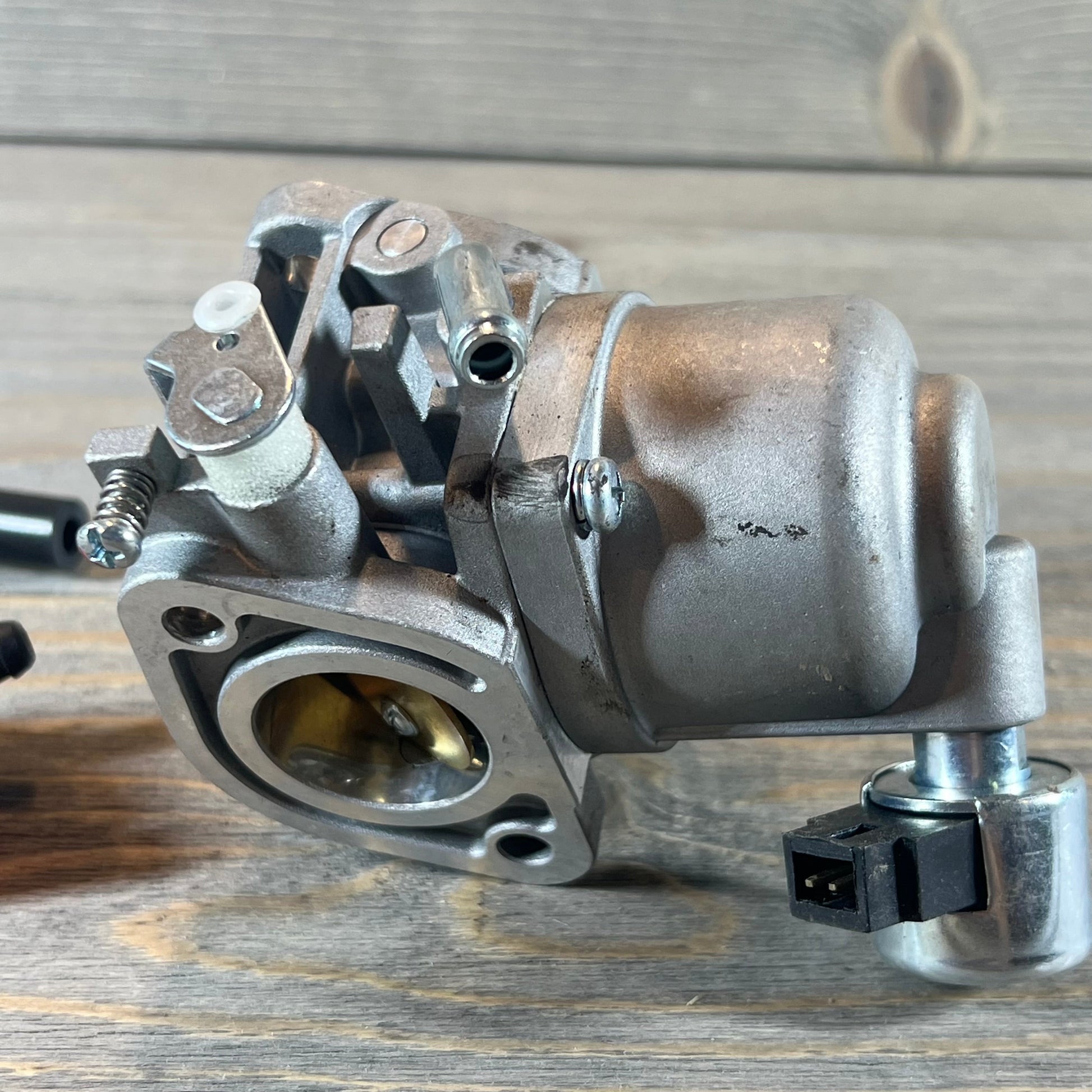 Carburetor for 40N777-0001-B1 engine, showcasing intricate components on wooden background.