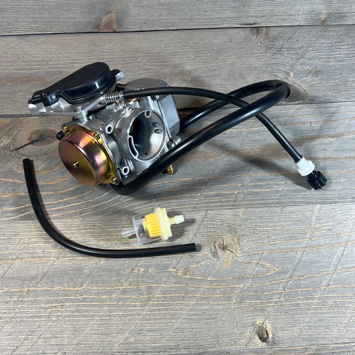Carburetor for Suzuki Eiger 400 LTF400 Manual 2002-2007 with filter and hoses on wooden background.