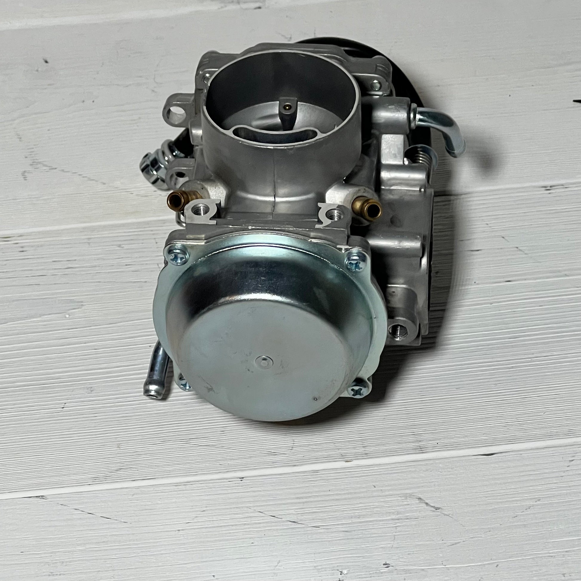 Carburetor for Suzuki LT-F250 Quadrunner 1990-1993, showcasing detailed front view on wooden surface.