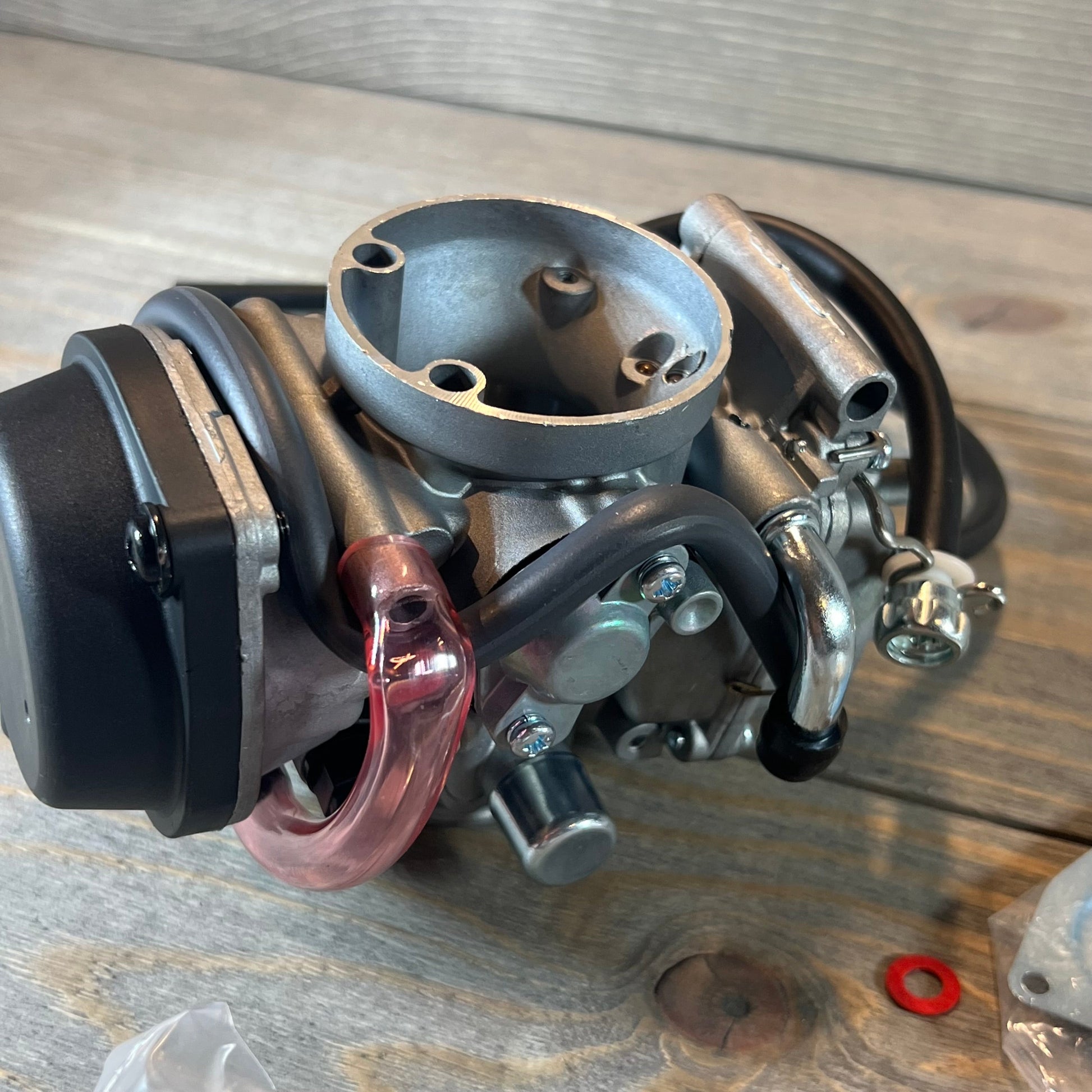 Carburetor replacement for Suzuki LTZ400 Quad 2003-2007, featuring attached fuel valve petcock, on wooden surface.