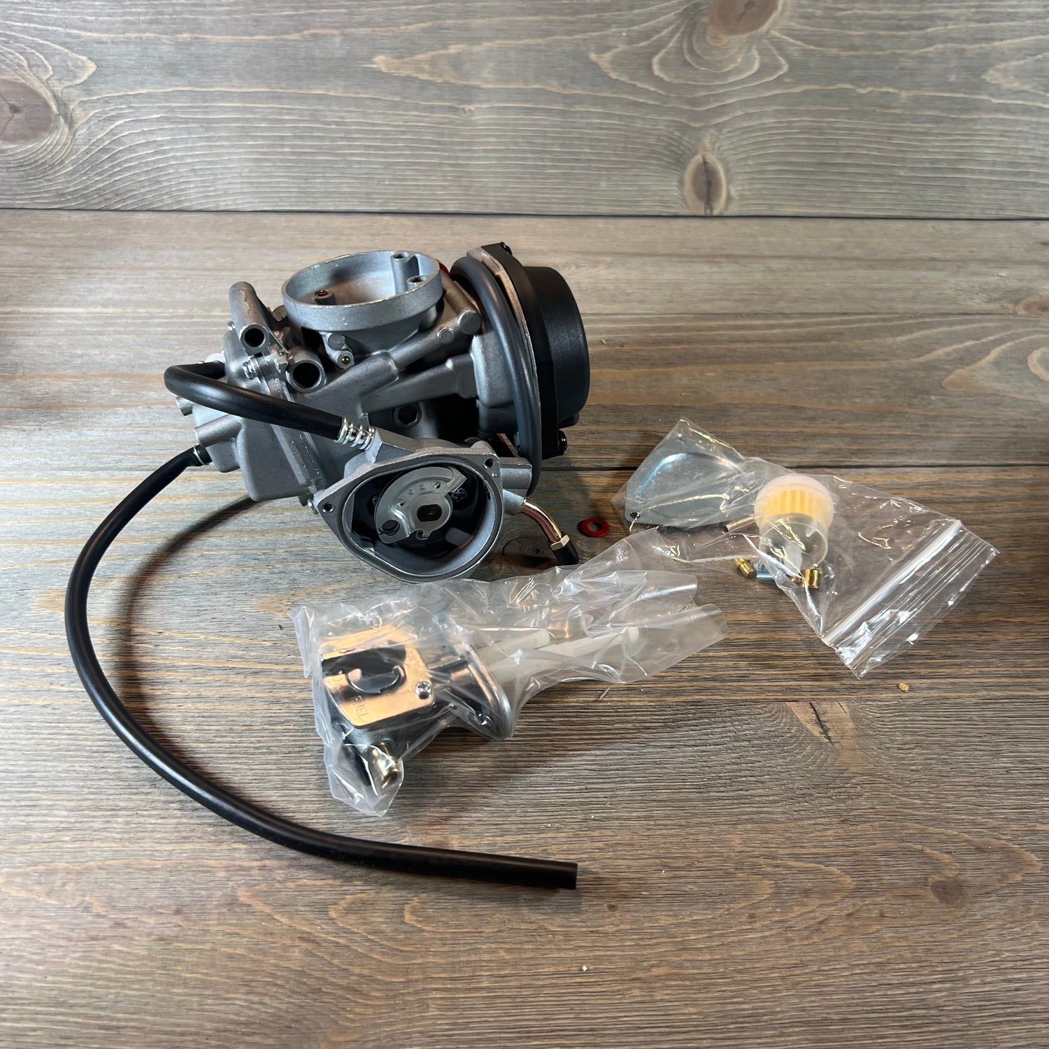 Carburetor replacement for Suzuki LTZ400 Quad 2003-2007 with fuel valve petcock, displayed on a wooden surface.