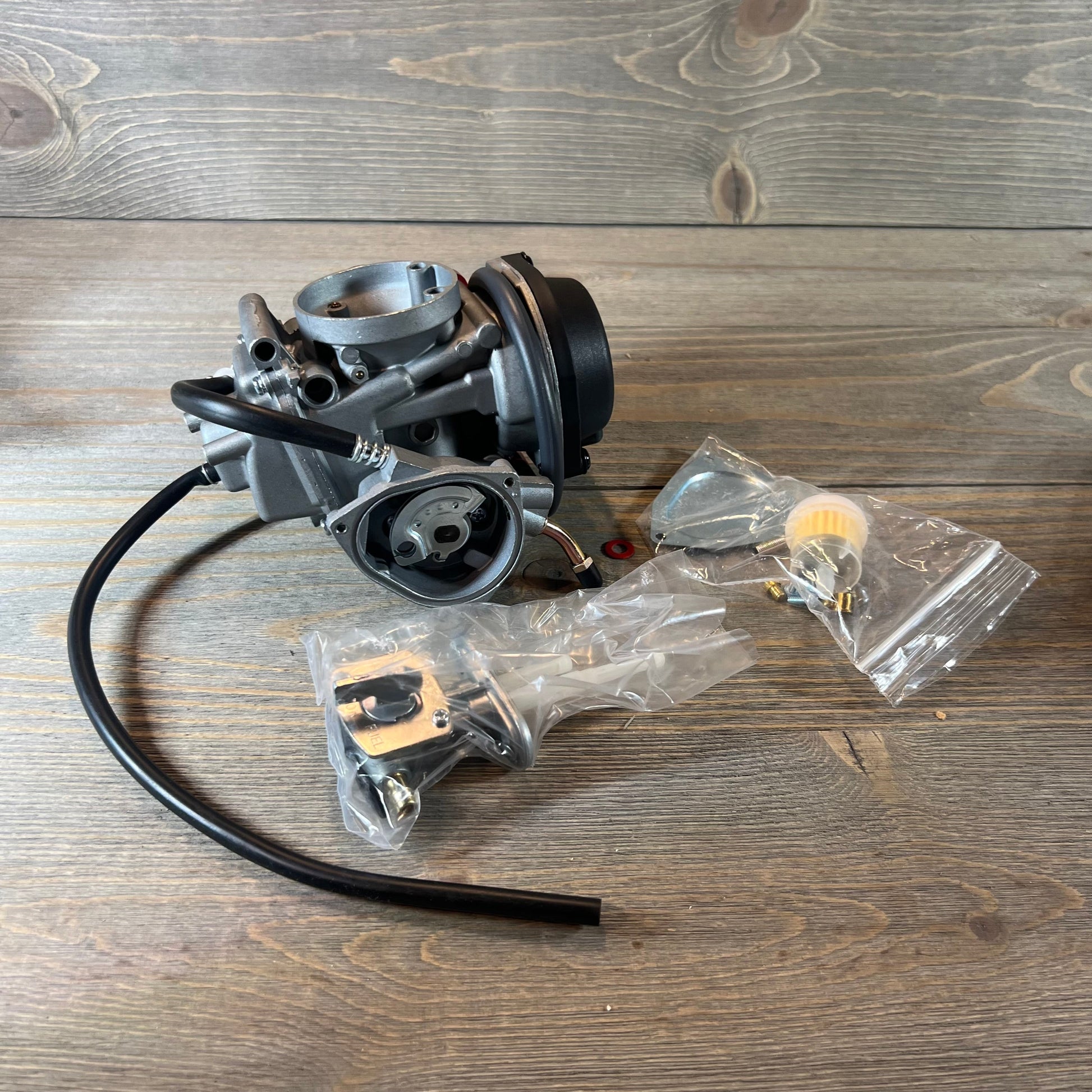 Carburetor replacement for Suzuki LTZ400 Quad 2003-2007 with fuel valve petcock, displayed on a wooden surface.