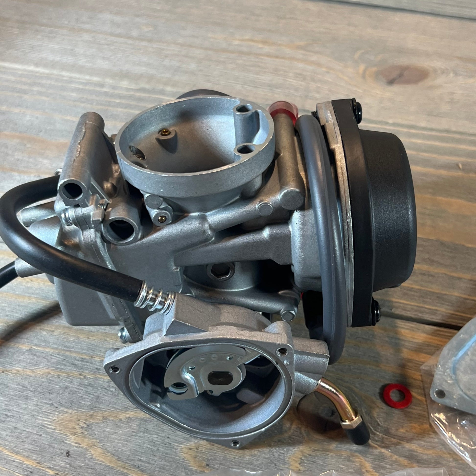 Carburetor replacement for Suzuki LTZ400 Quad, detailed view with fuel valve petcock on wooden surface.