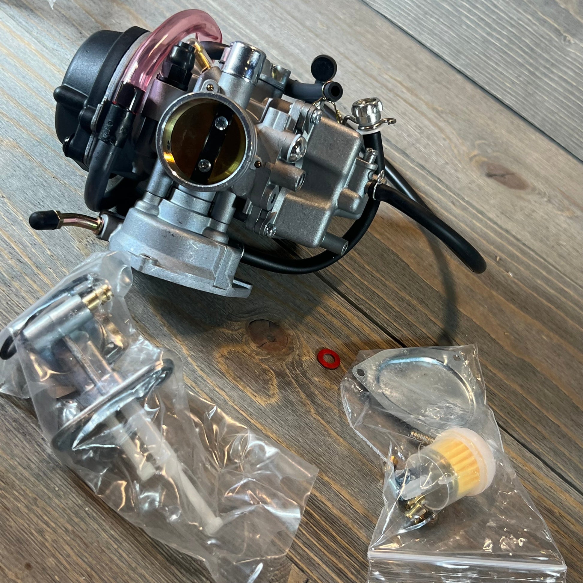 Carburetor replacement kit for Suzuki LTZ400 Quad 2003-2007 with fuel valve petcock on a wooden surface.