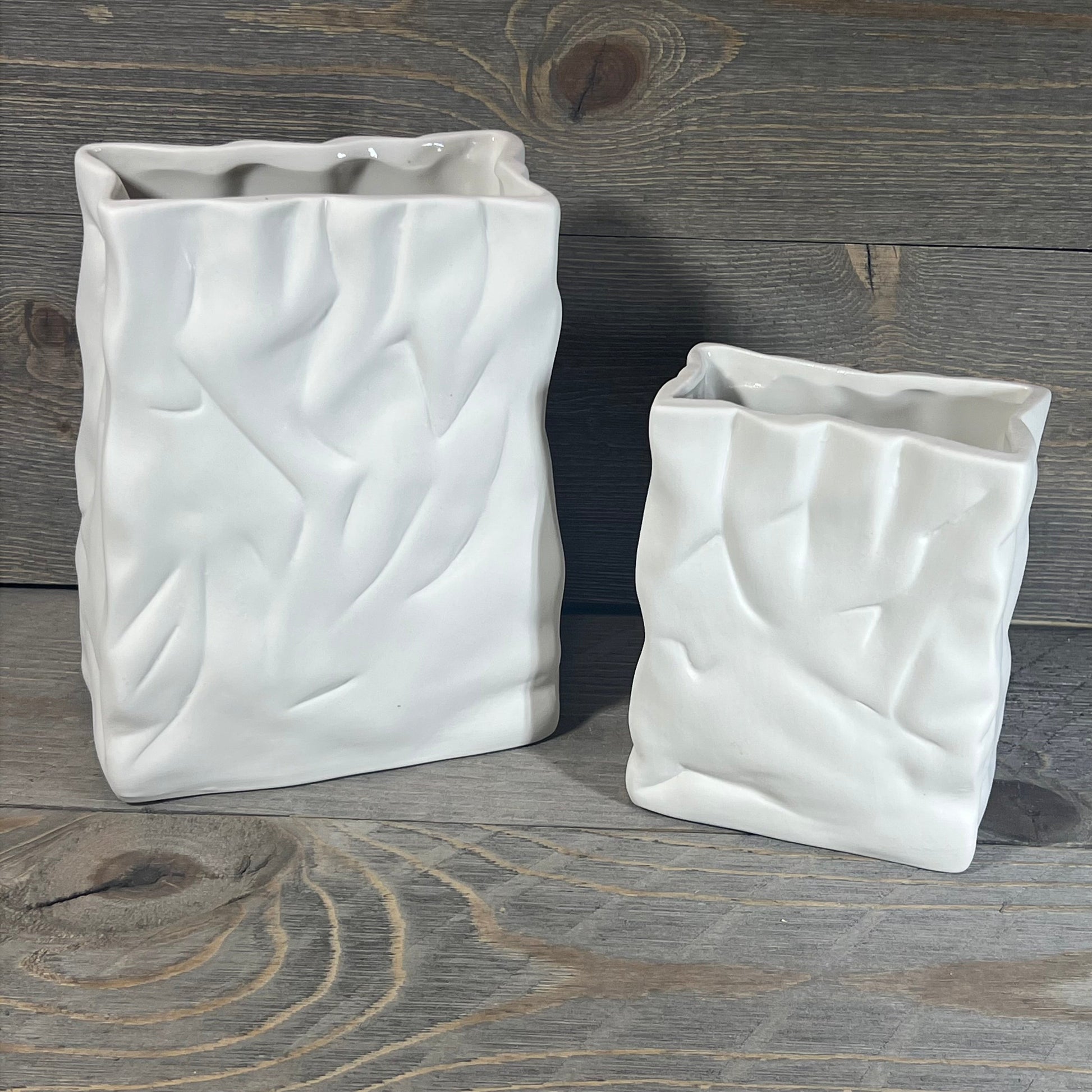 Ceramic vase set with crinkle paper bag design in crème and coconut café finish on rustic wood background.