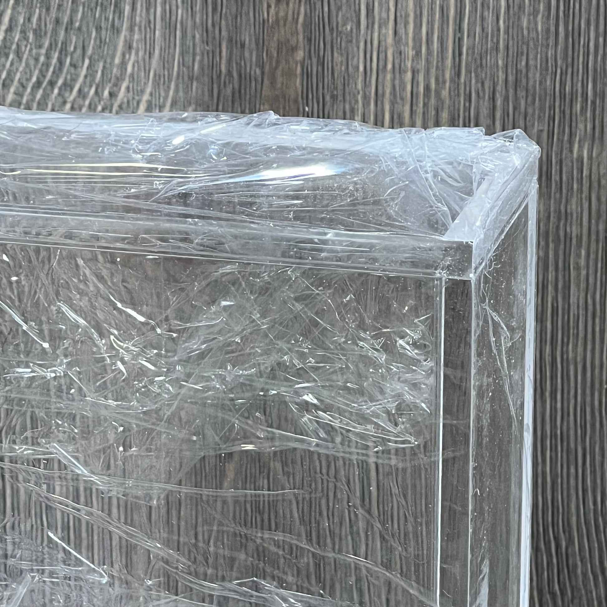 Clear acrylic magnetic case for TCG booster box, wrapped in protective plastic, ideal for collectors.