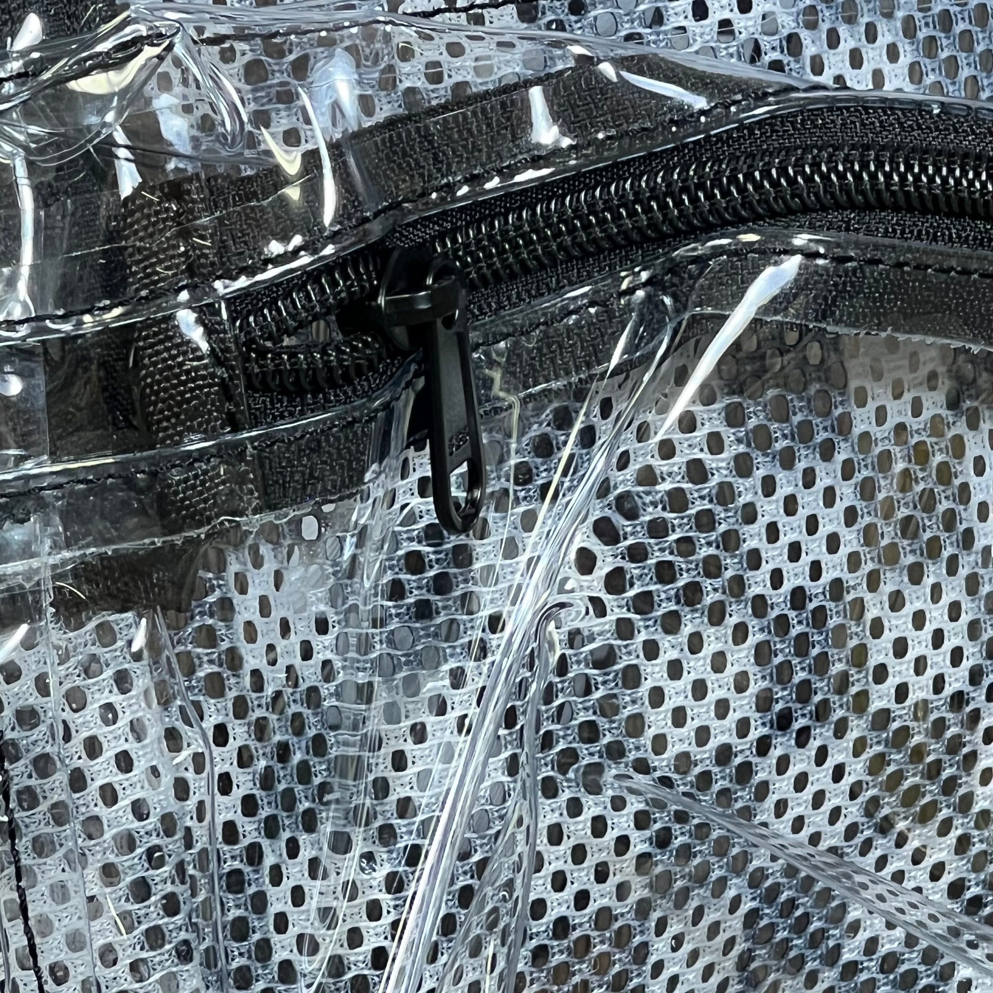 Close-up of clear mini backpack zipper, showcasing durable black stitching and transparent design for stadium events and concerts.