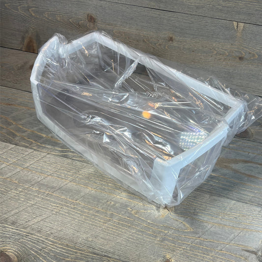 Clear Whirlpool refrigerator door shelf bin replacement WPW10224961 wrapped in plastic, resting on wooden surface.