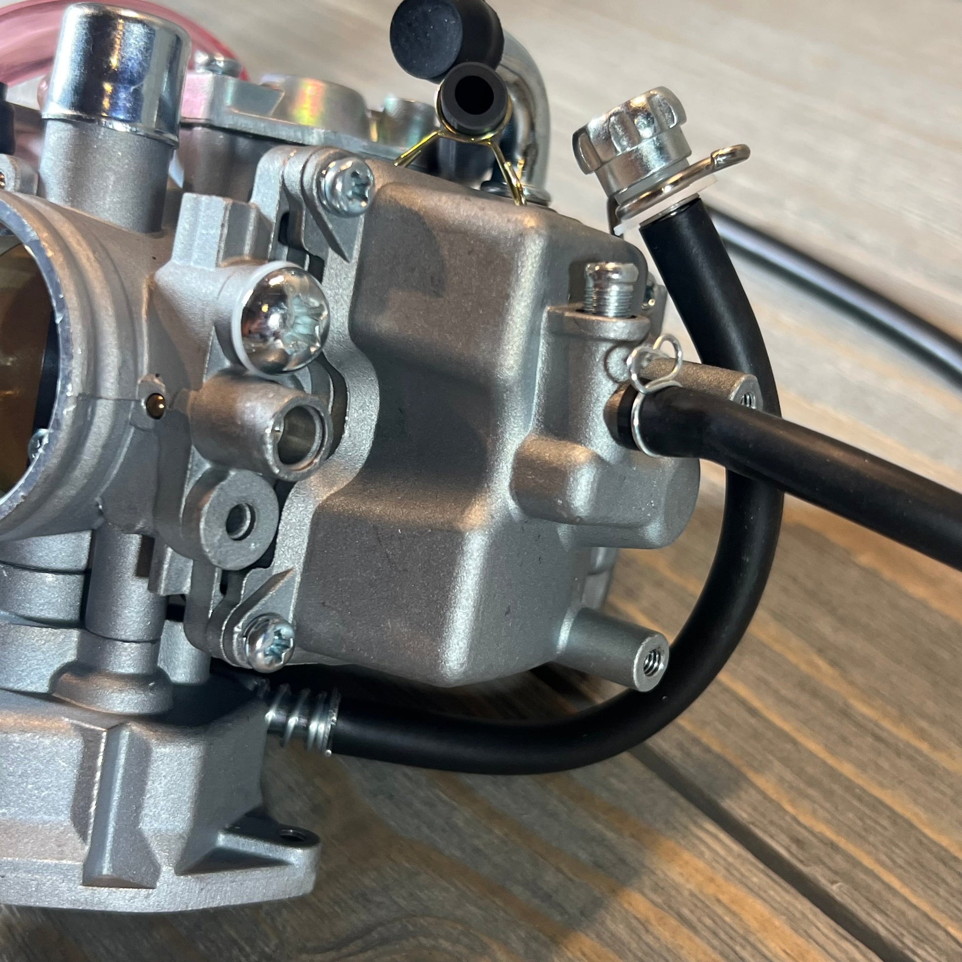 Close-up of carburetor replacement for Suzuki LTZ400 Quad, showing fuel valve petcock connection detail.