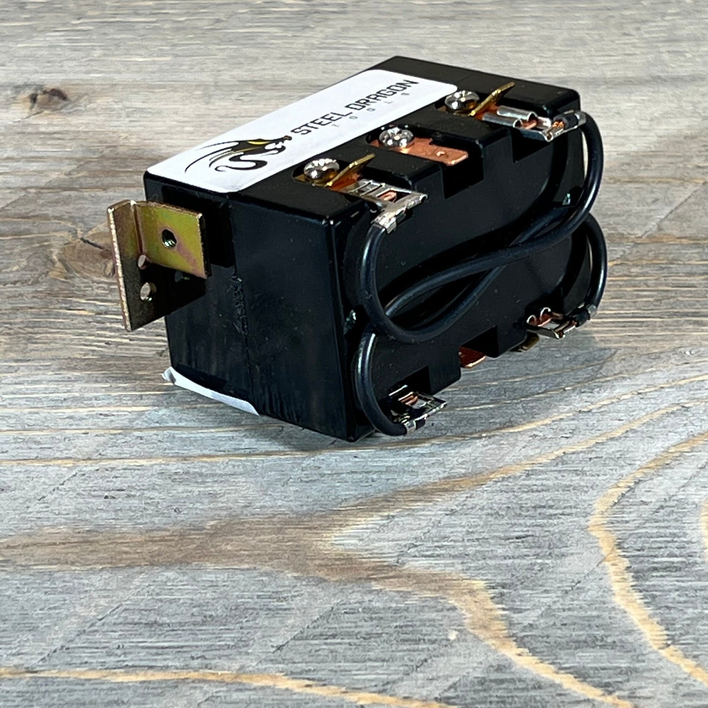 Close-up of Steel Dragon Tools forward reverse switch, showcasing copper connectors and wiring on a wooden surface.