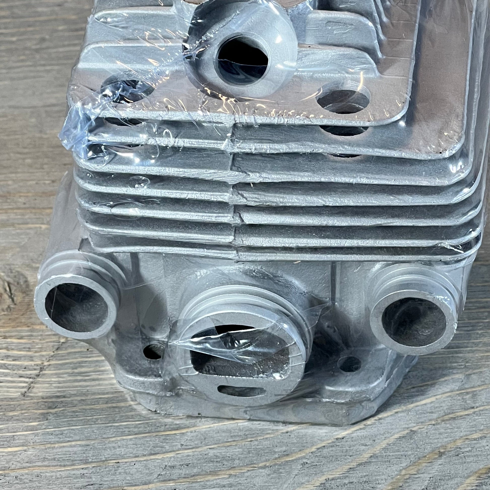 Close-up of Yingspart 56mm cylinder piston kit for Stihl TS700 TS800, showcasing detailed metalwork on a wooden surface.
