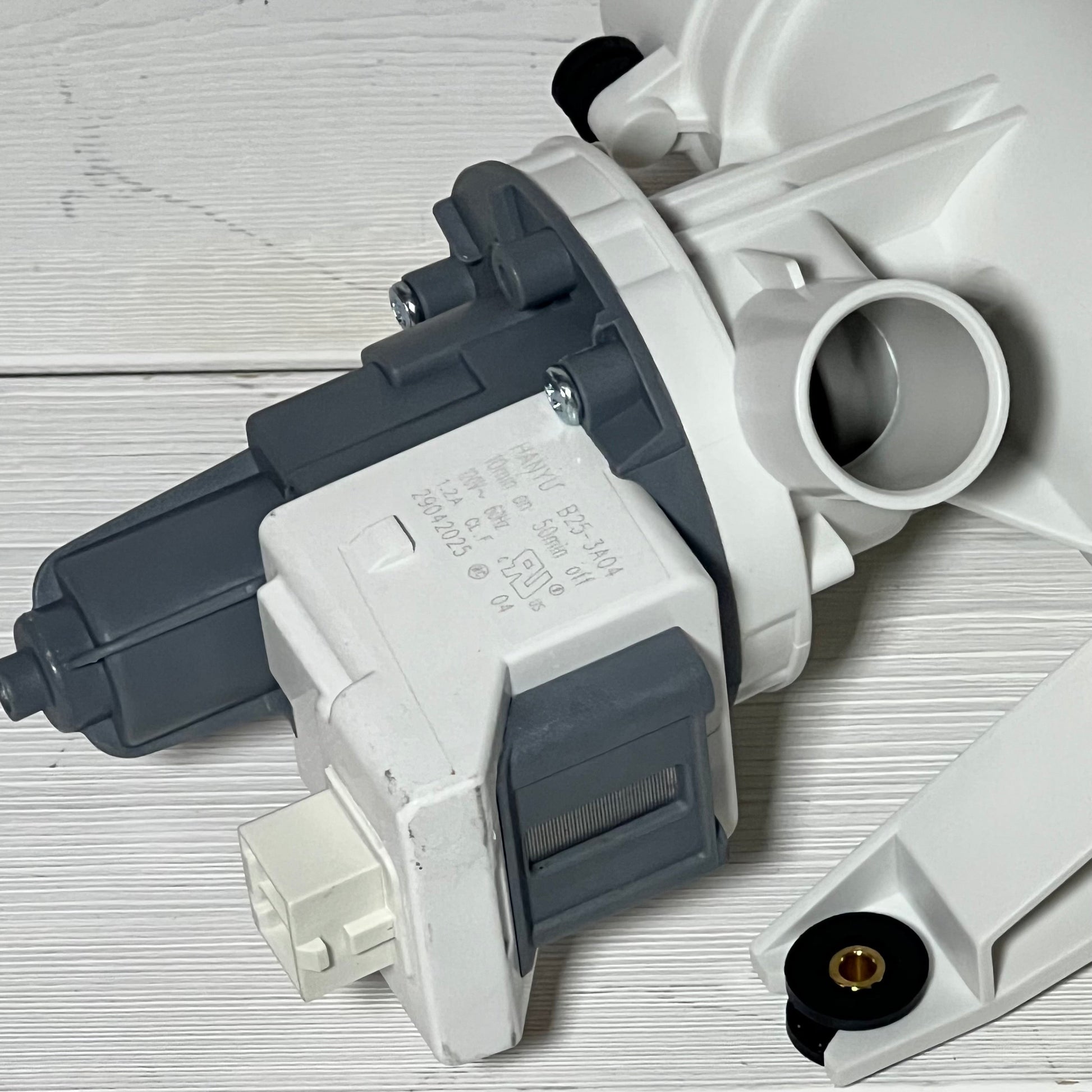 Close-up view of G.E compatible washer drain pump and filter, showcasing connection details and design features.