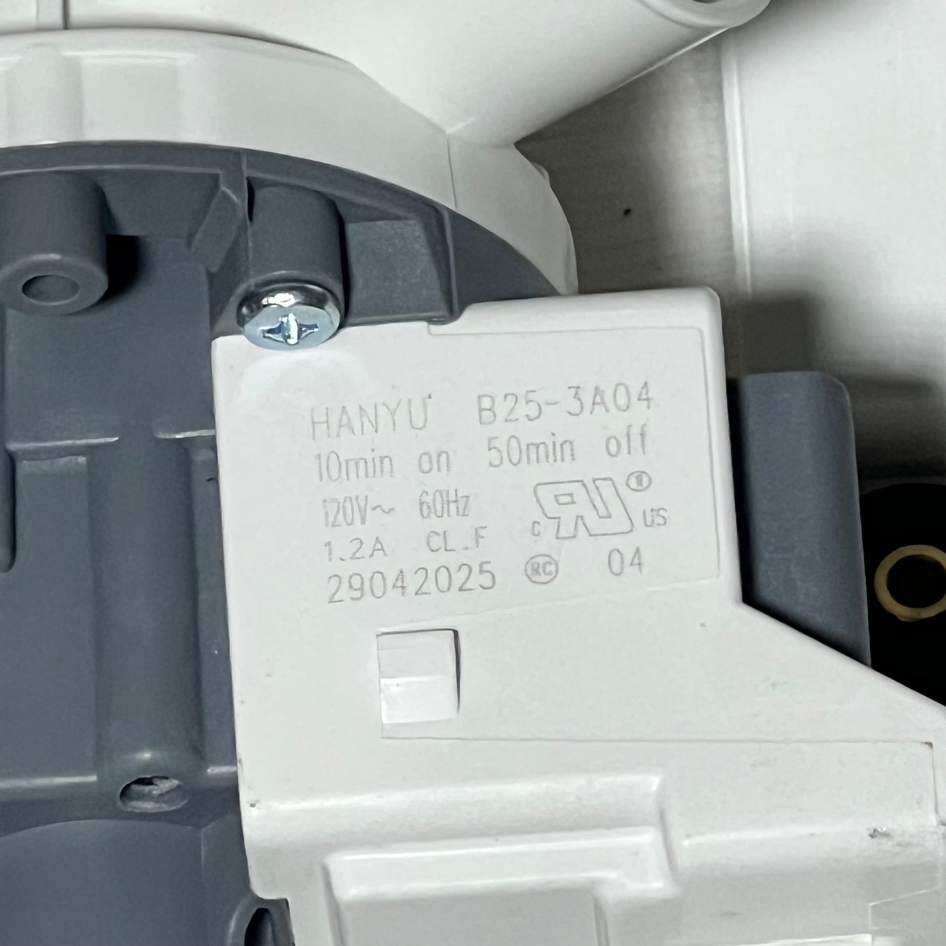 Close-up view of G.E washer drain pump and filter, showcasing label and detailed specifications.