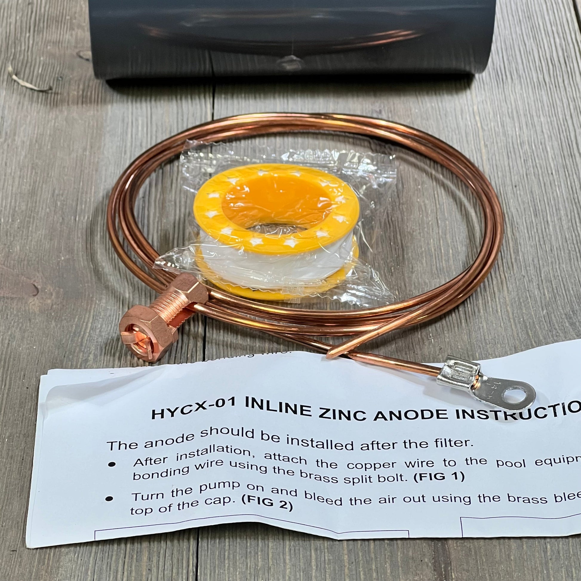 Copper wire and fittings for 1047076874-briidea 2'' inline zinc anodes, with installation guide on wooden surface.