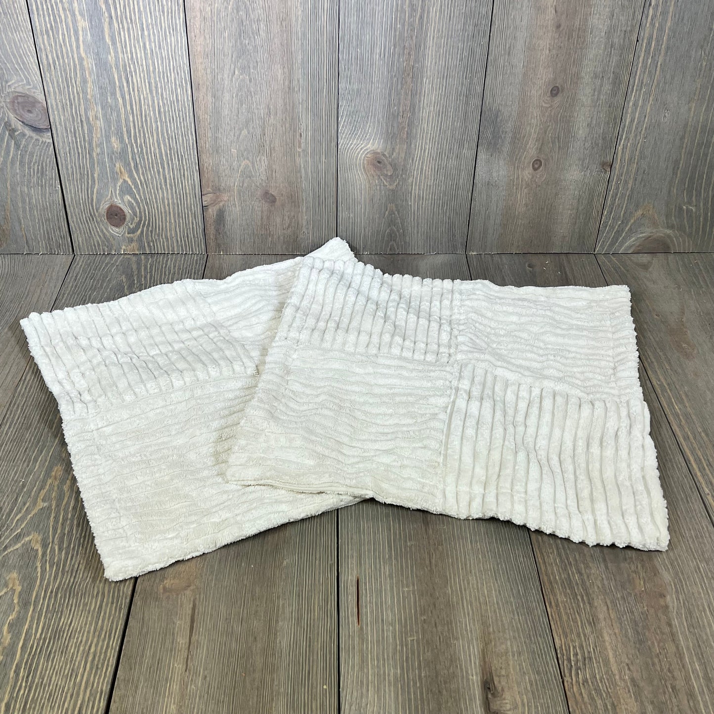 Cream corduroy throw pillow covers with cross patchwork on rustic wooden background, ideal for farmhouse decor.