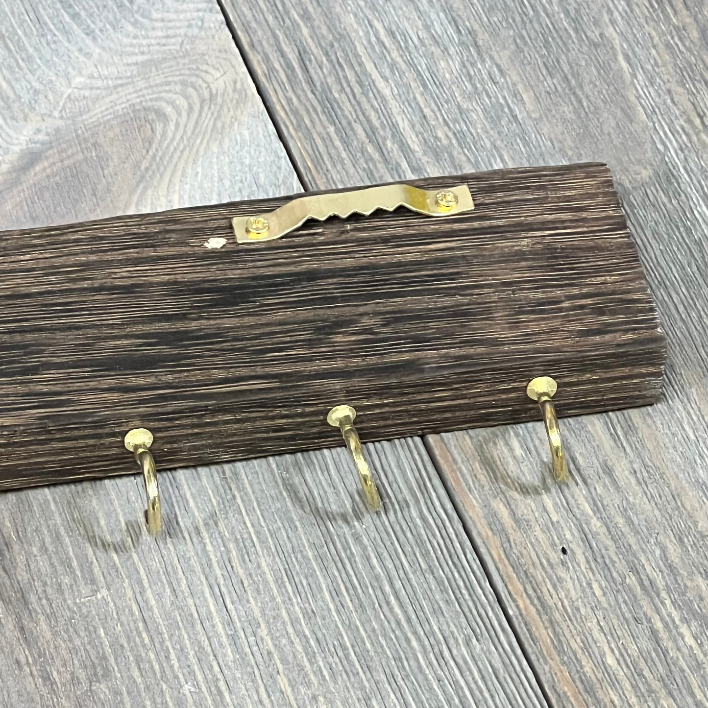 Rustic wooden barn door jewelry organizer with gold hooks for necklaces and bracelets, wall-mounted storage solution.