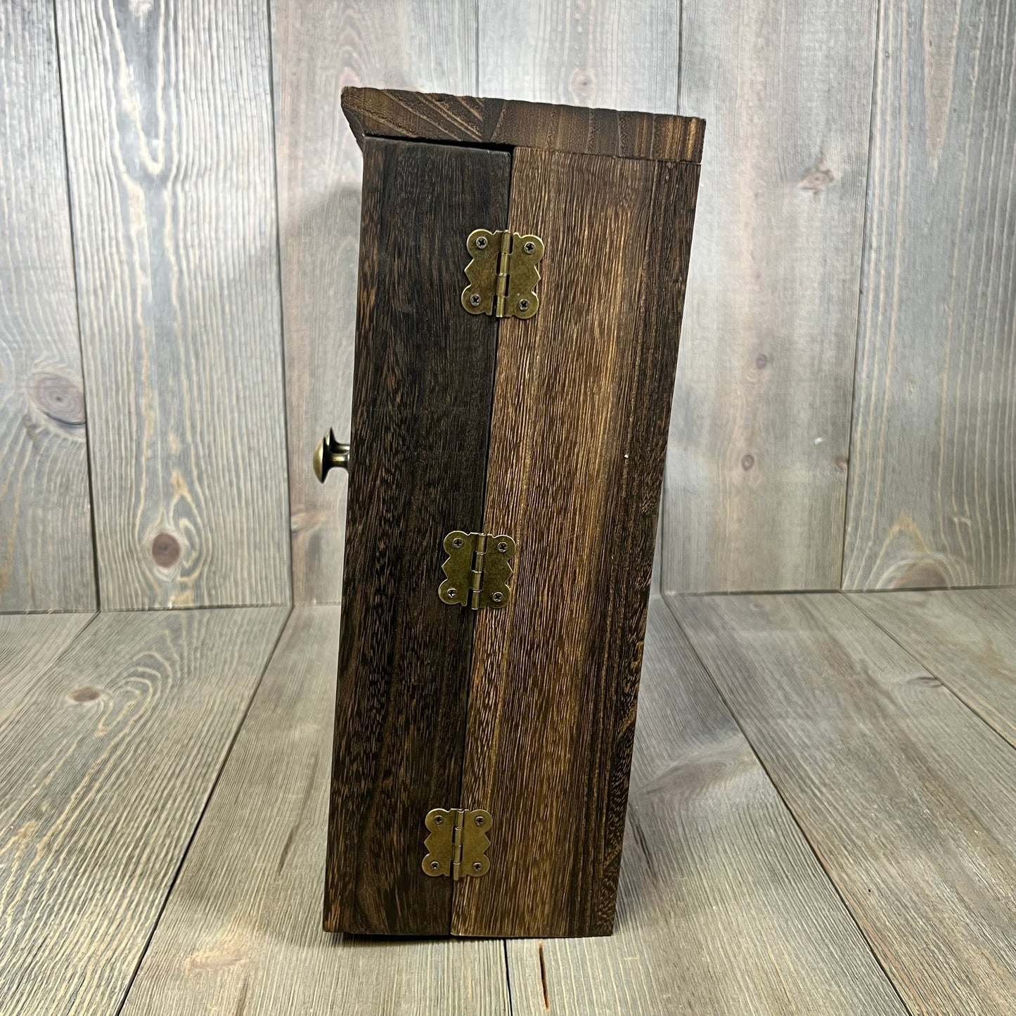 Rustic wooden barn door jewelry organizer with brass hinges, perfect for wall-mounted necklace and earring storage.