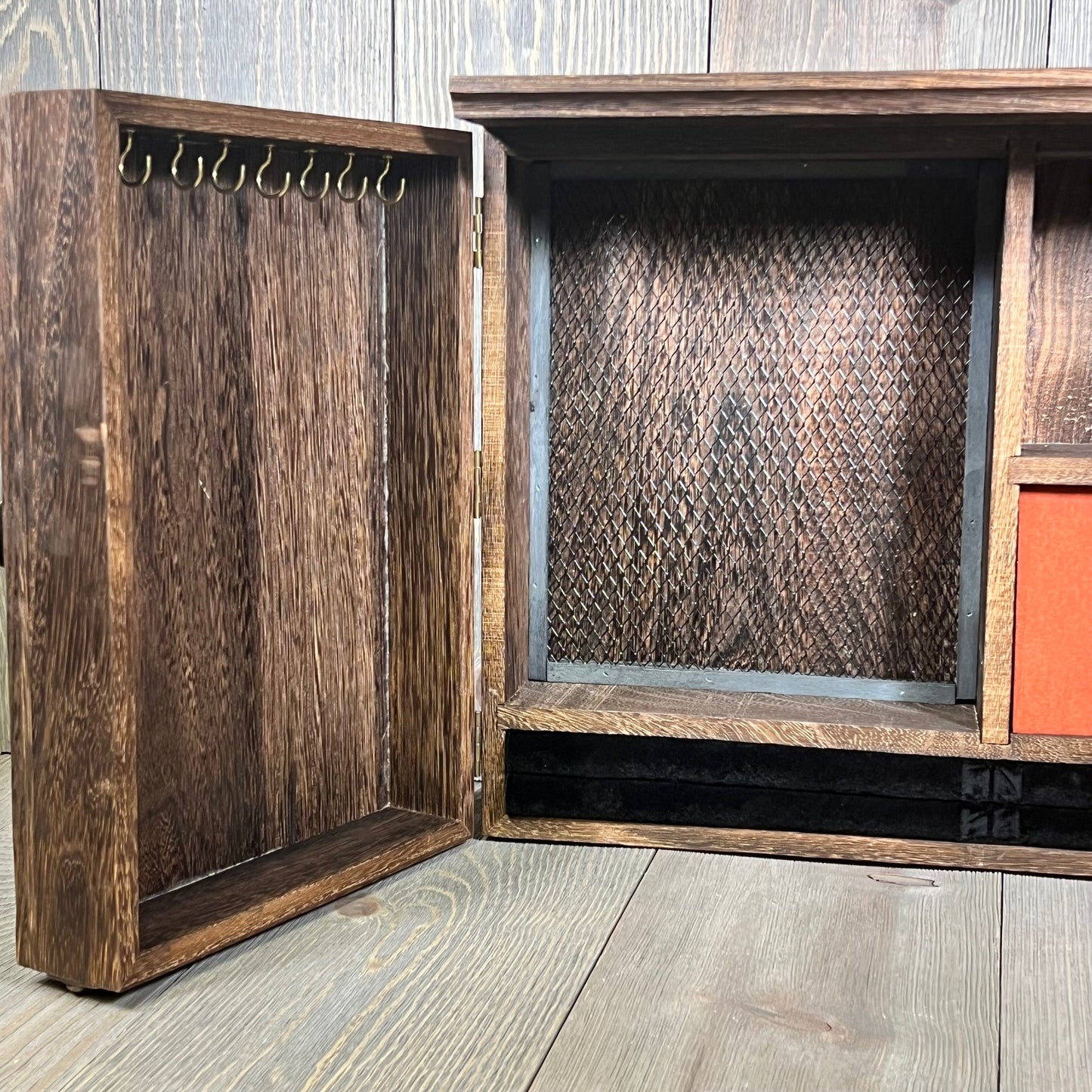 Rustic wooden barn door jewelry organizer with hooks and mesh for necklaces and earrings, perfect for wall mounting.