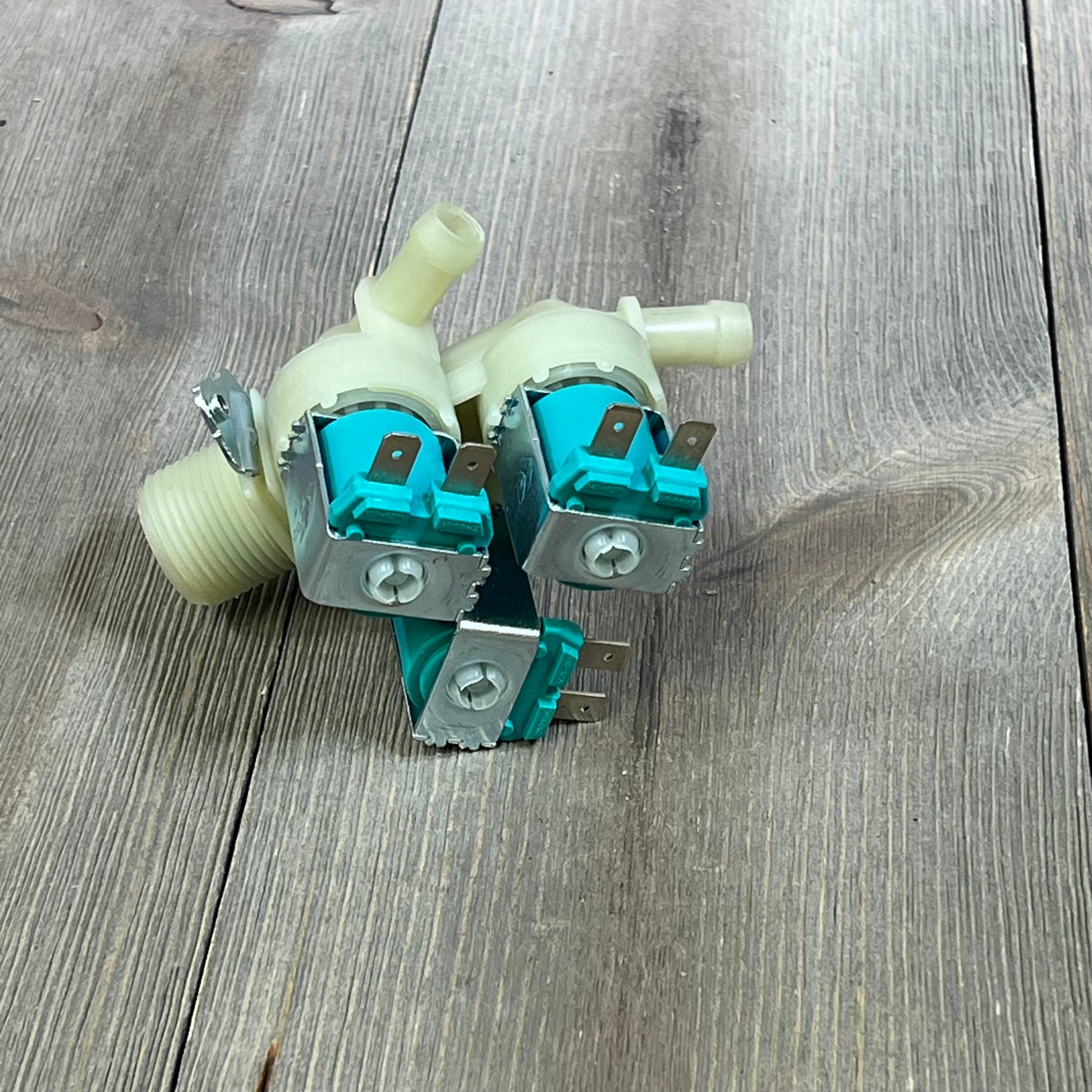 LG Kenmore washer water inlet valve set on wooden surface, showcasing dual valve design for hot and cold water compatibility.