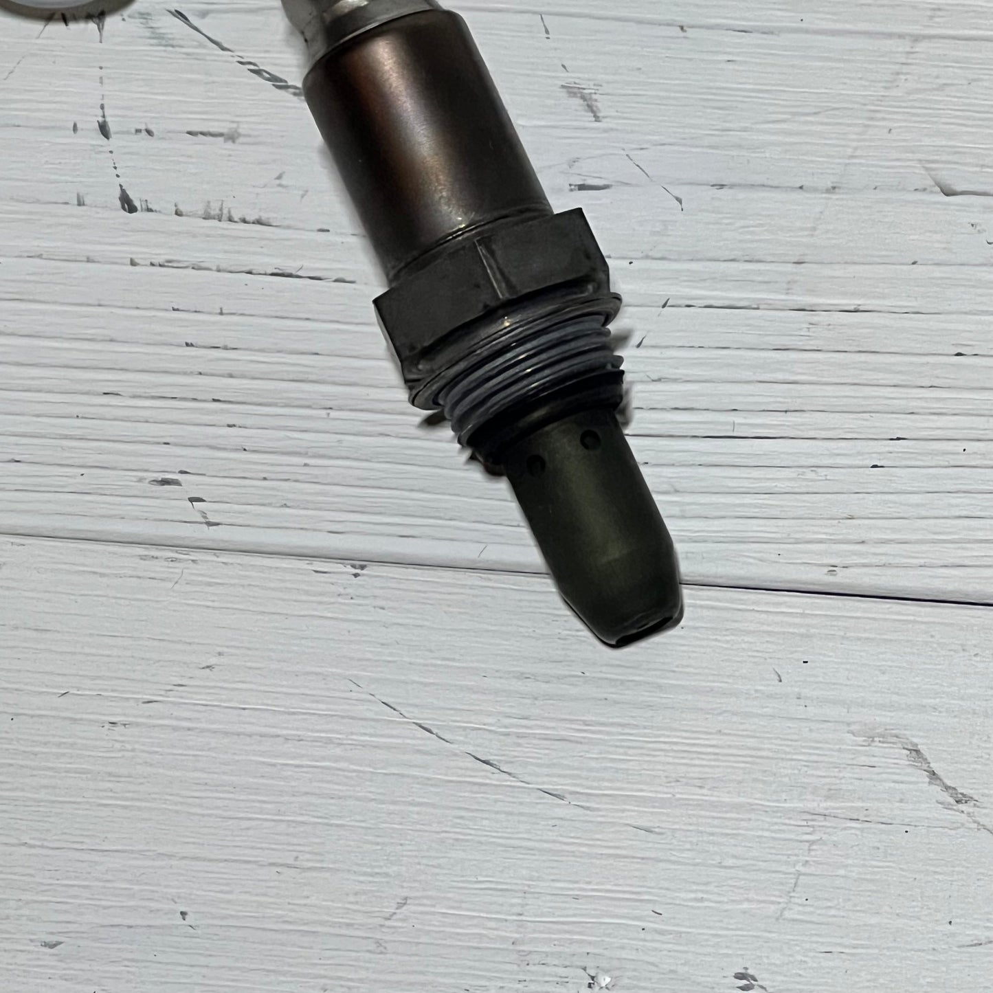 Upstream oxygen sensor for Nissan Rogue 2.5L, 2010-2013, shown on a white wood background.