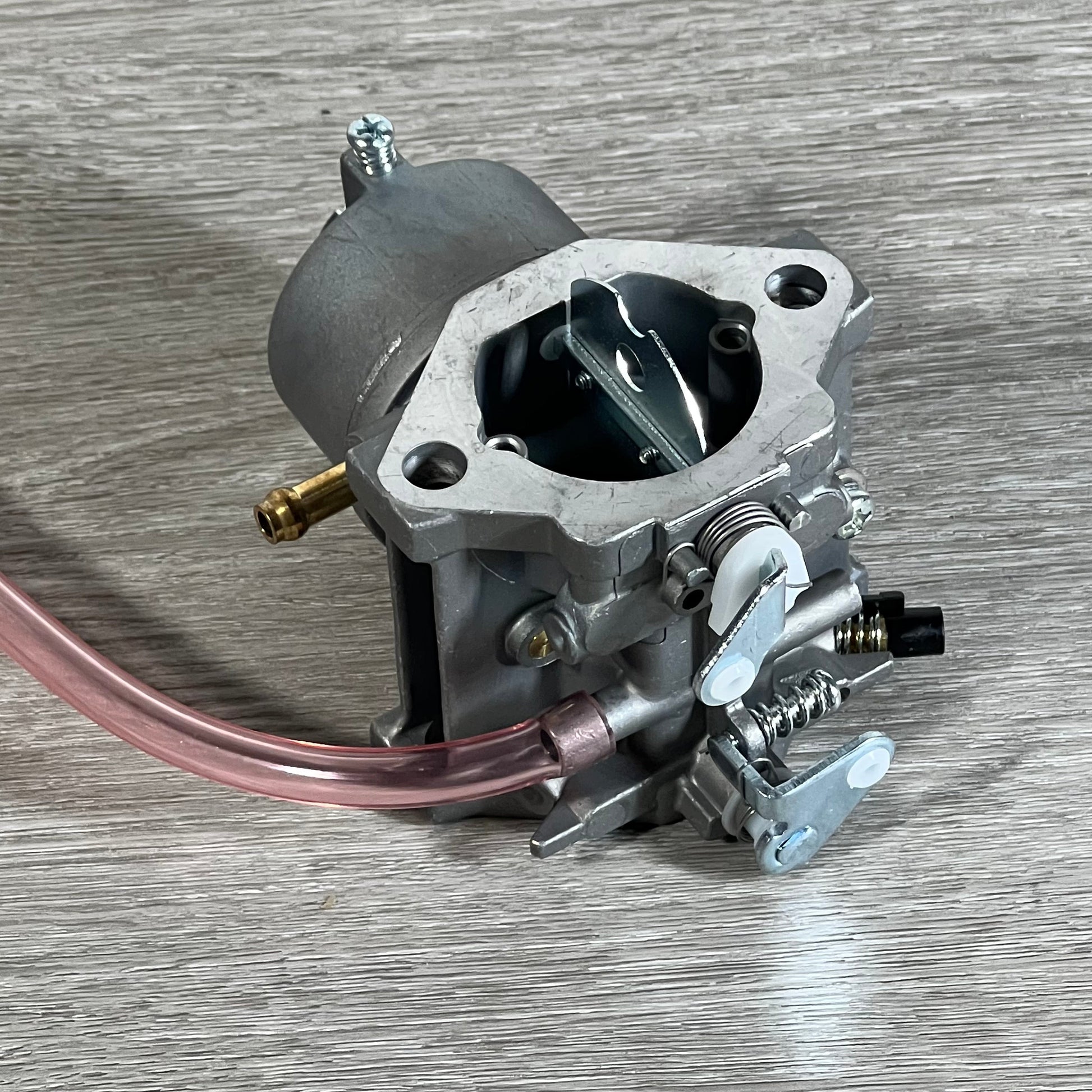 Durable Cylinman carburetor for John Deere mowers, showcasing intricate design and metal finish on wooden surface.