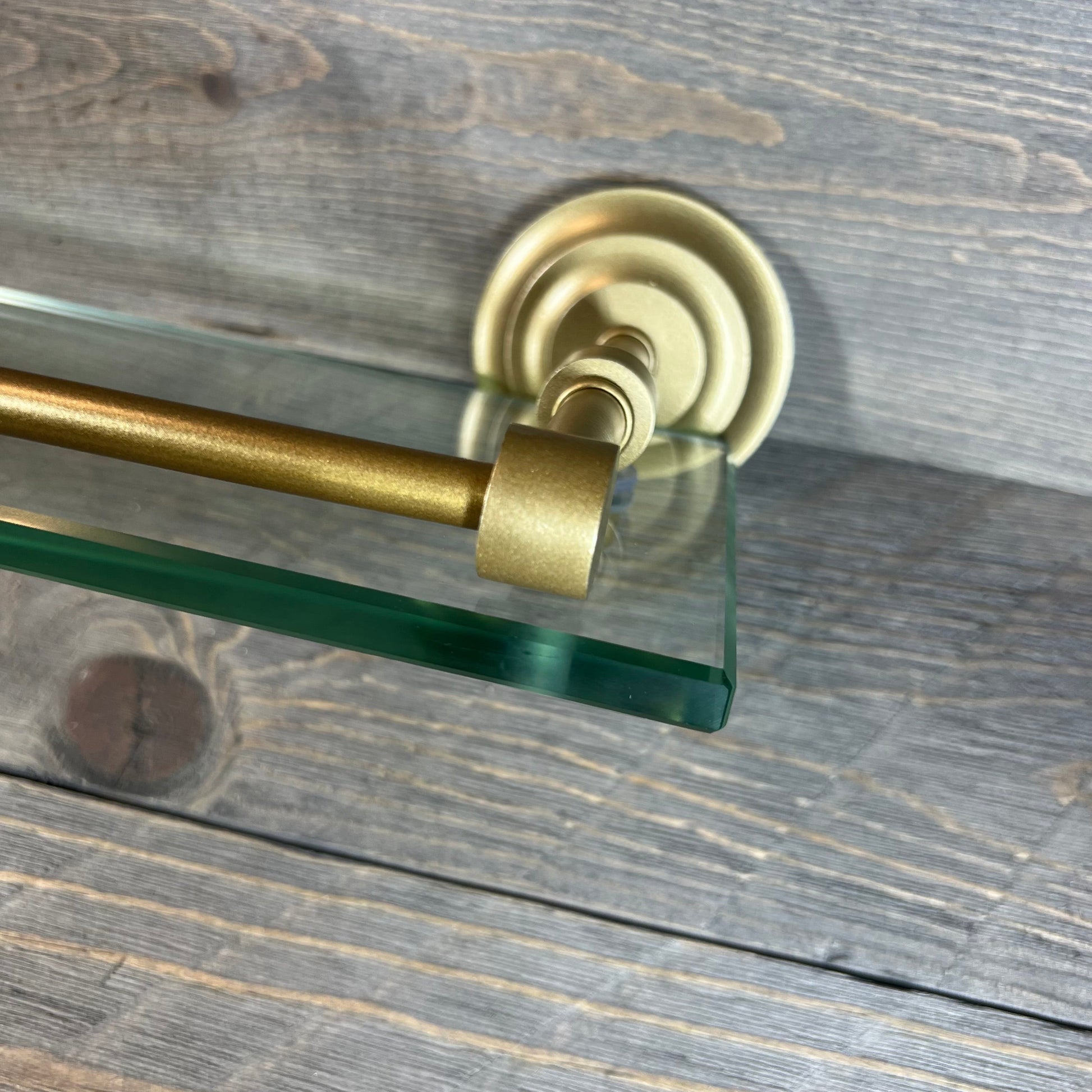 Elegant brass paper towel holder with sleek 22" glass shelf, mounted on textured wood background.