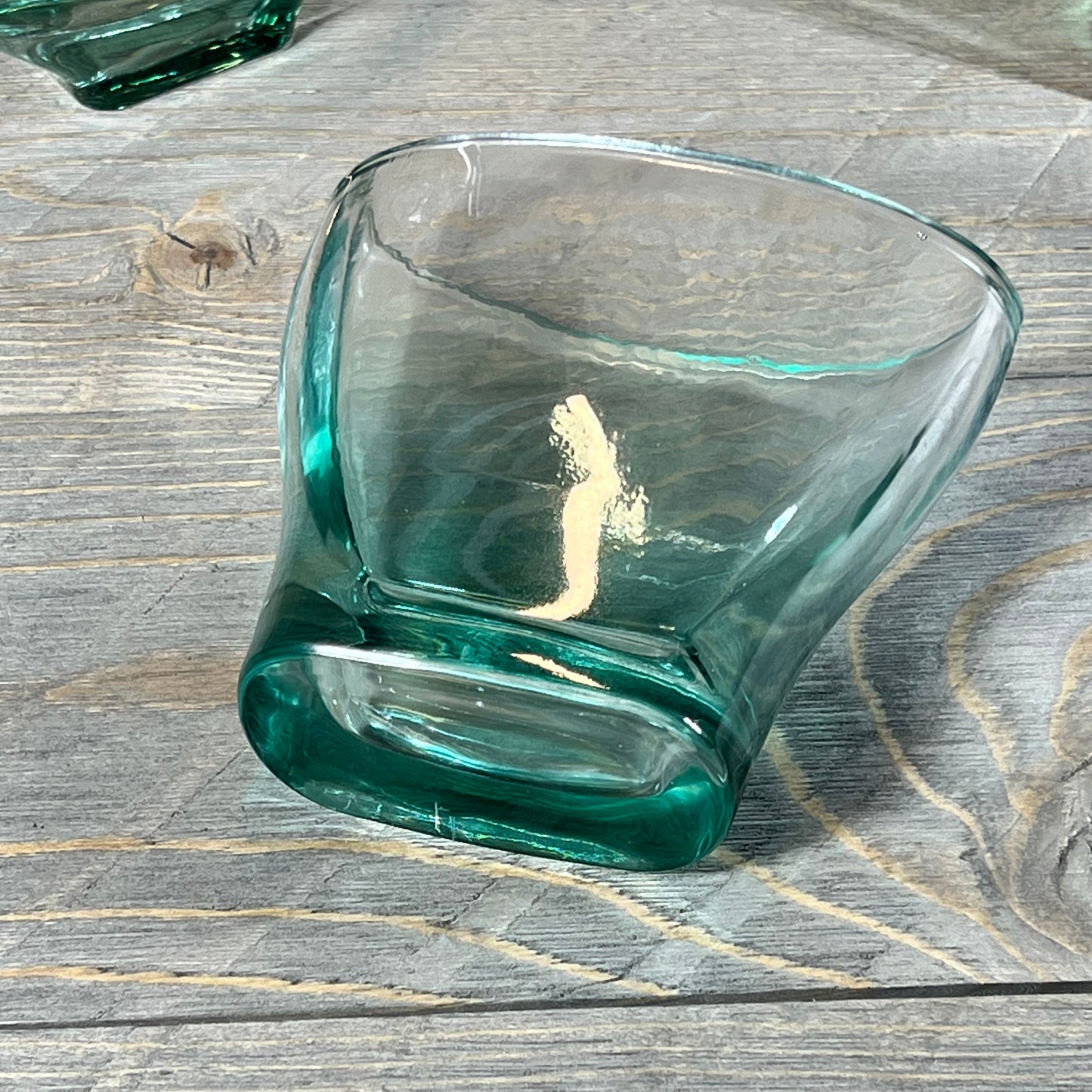 Elegant green teal glass tumbler from a 5-piece bathroom accessory set on a wooden surface.