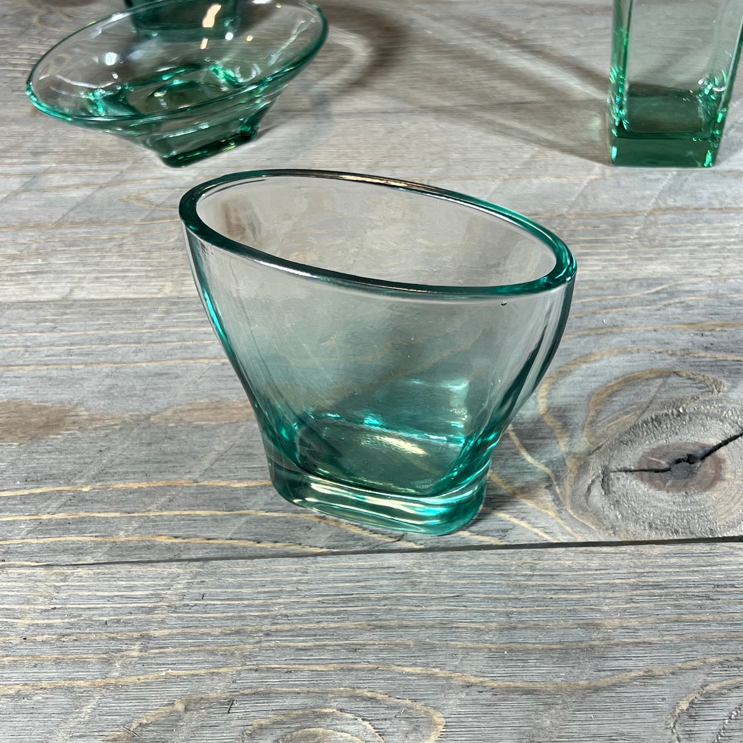 Elegant teal glass tumbler from the Green Teal Glass Bathroom Accessory Set on rustic wooden surface.