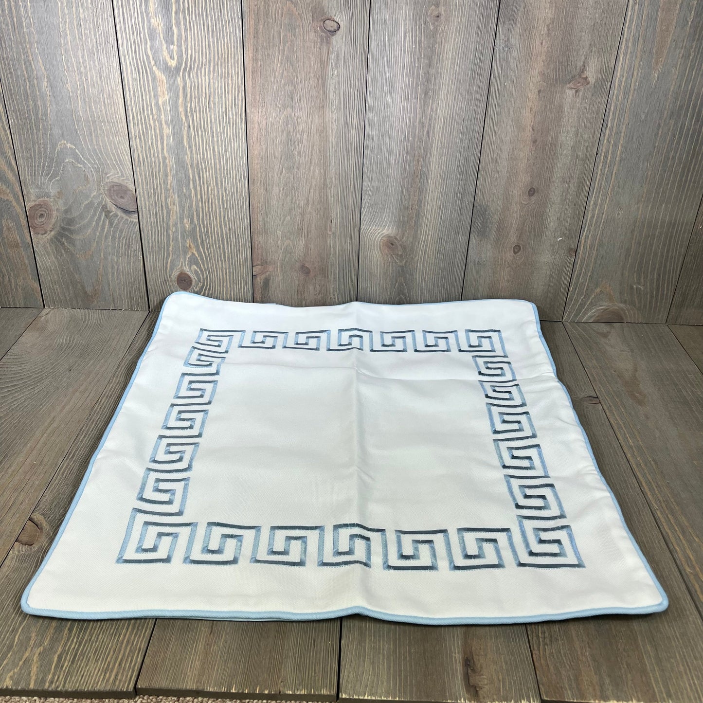 Baby blue embroidered Greek key pillow cover on wooden surface, showcasing premium quality and water-repellent fabric.