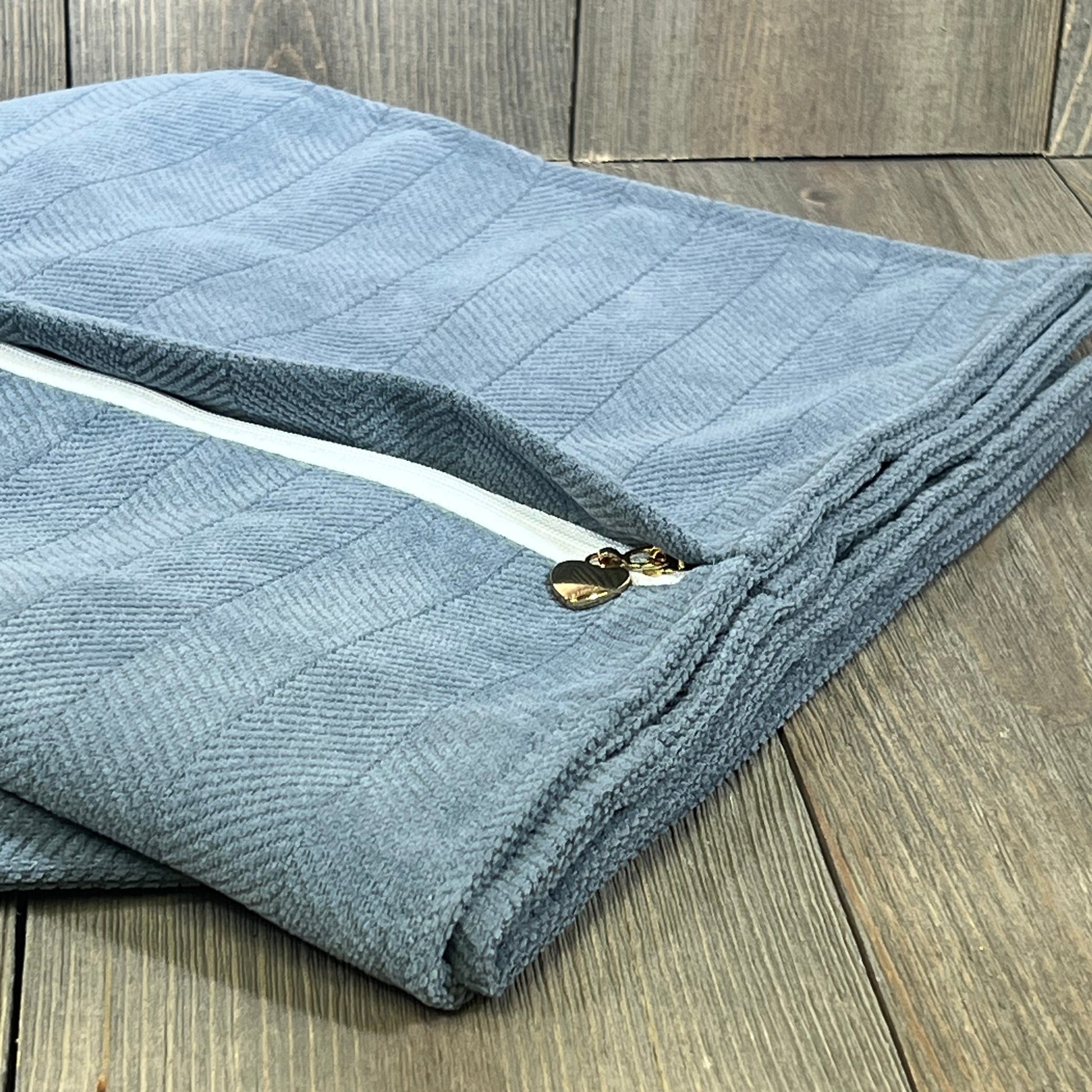 Dusty blue chenille pillow covers 26x26 with elegant design, perfect for couch or bed decor, folded on a wooden surface.