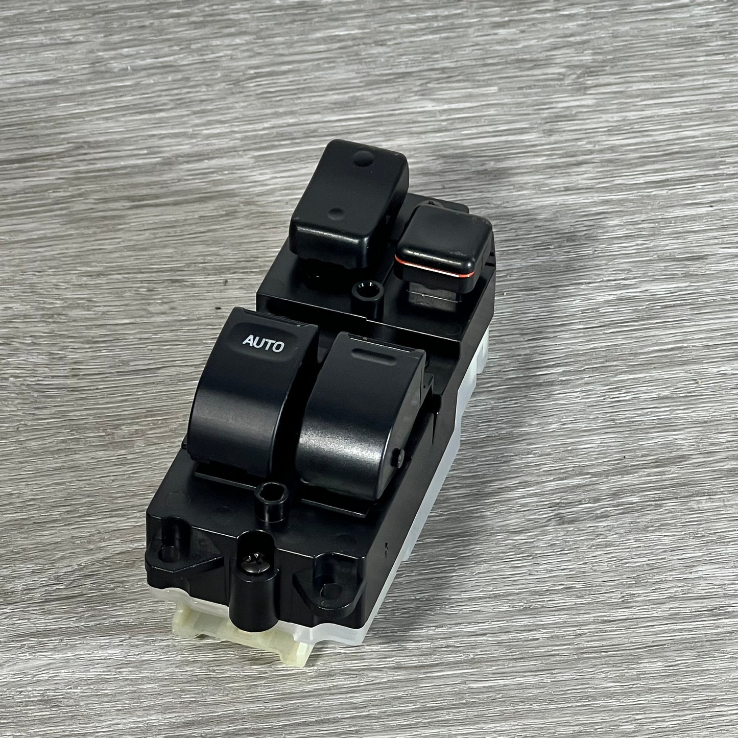 Front view of Dorman 901-711 window switch for Toyota, showcasing buttons and black casing on a wooden surface.
