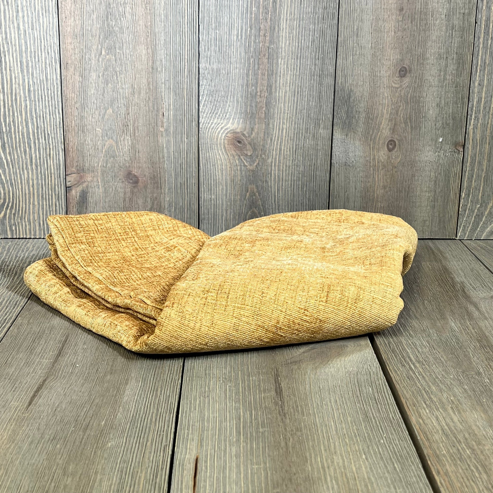 Cozy chenille gold throw pillow covers folded on a wooden surface, perfect for enhancing couch and sofa decor.