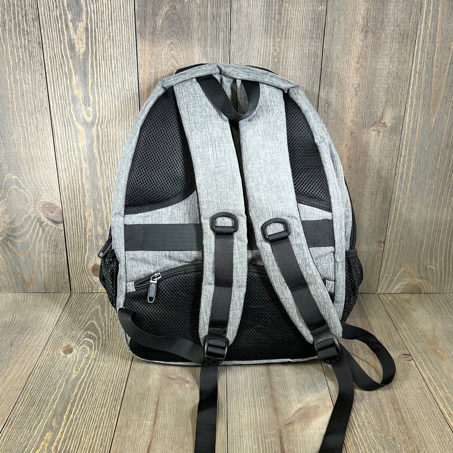 Grey MATEIN travel laptop backpack, showcasing adjustable padded straps and durable back support on a wooden floor.