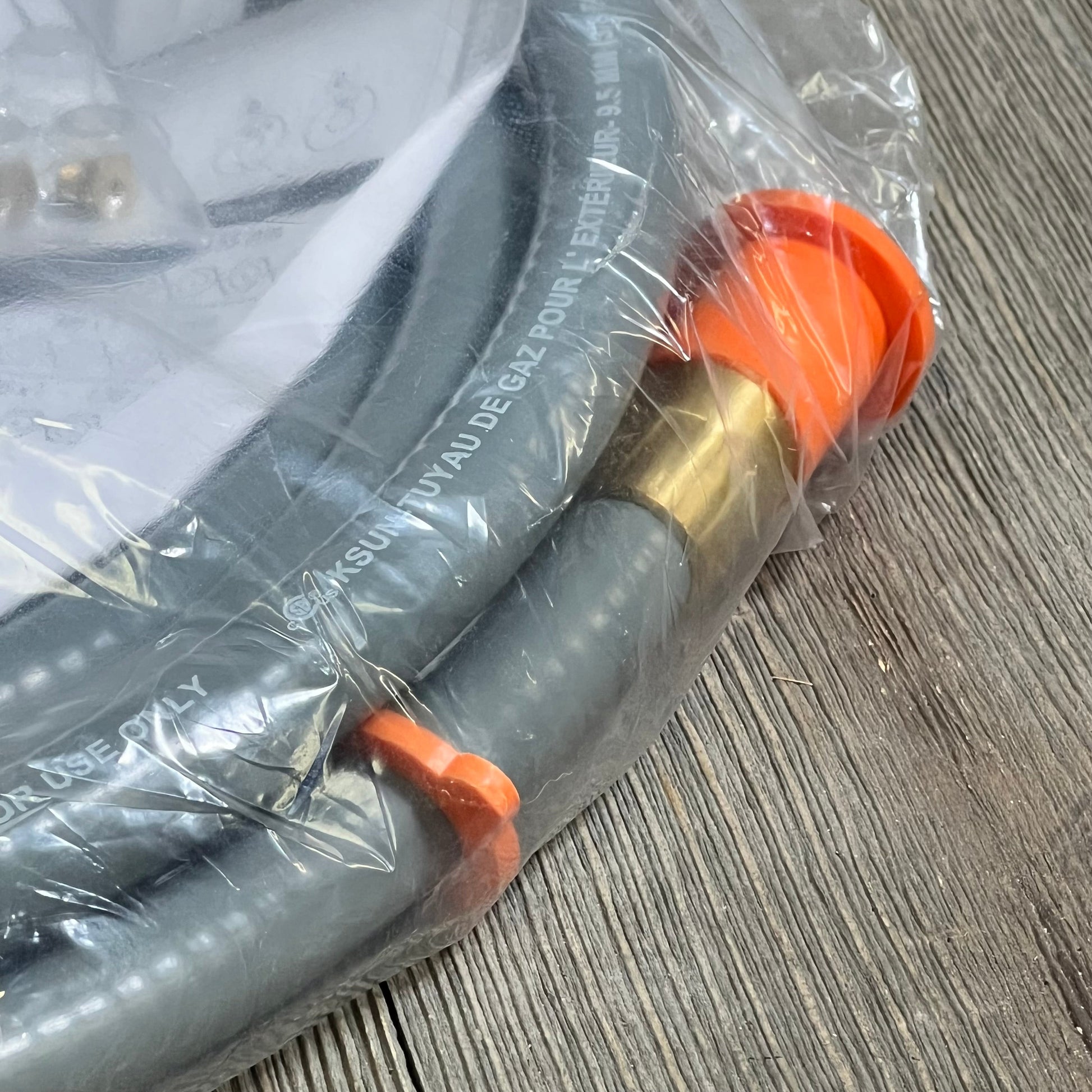 Gray Blackstone 5249 conversion kit with orange and brass connectors for propane to natural gas on a wooden surface.