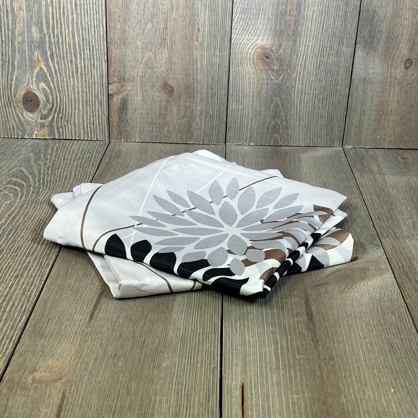Folded DFXSZ outdoor pillow covers with elegant black and brown geometric design on rustic wooden background.