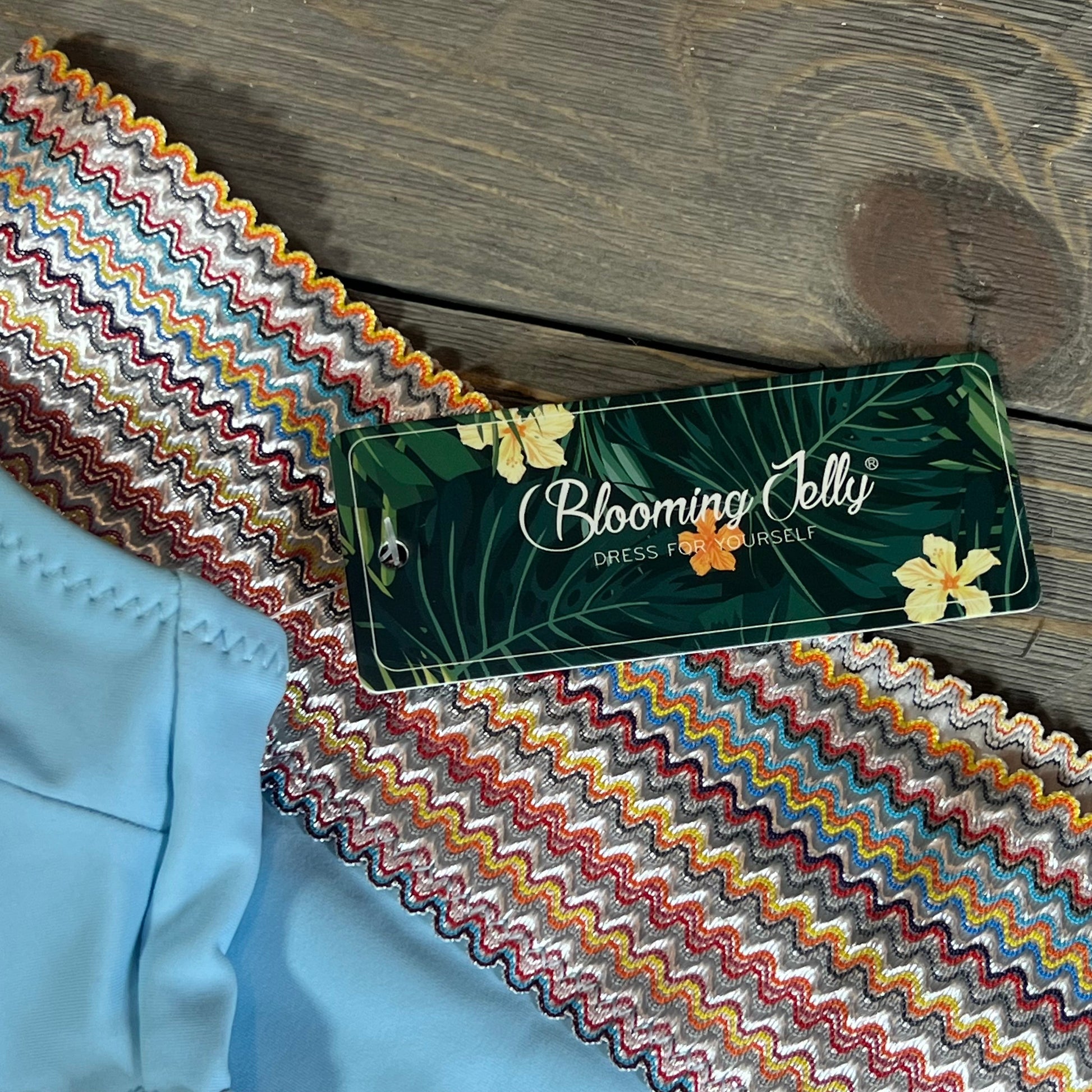 High-waisted bikini set in blue with colorful zigzag waistband detail, Blooming Jelly tag visible.