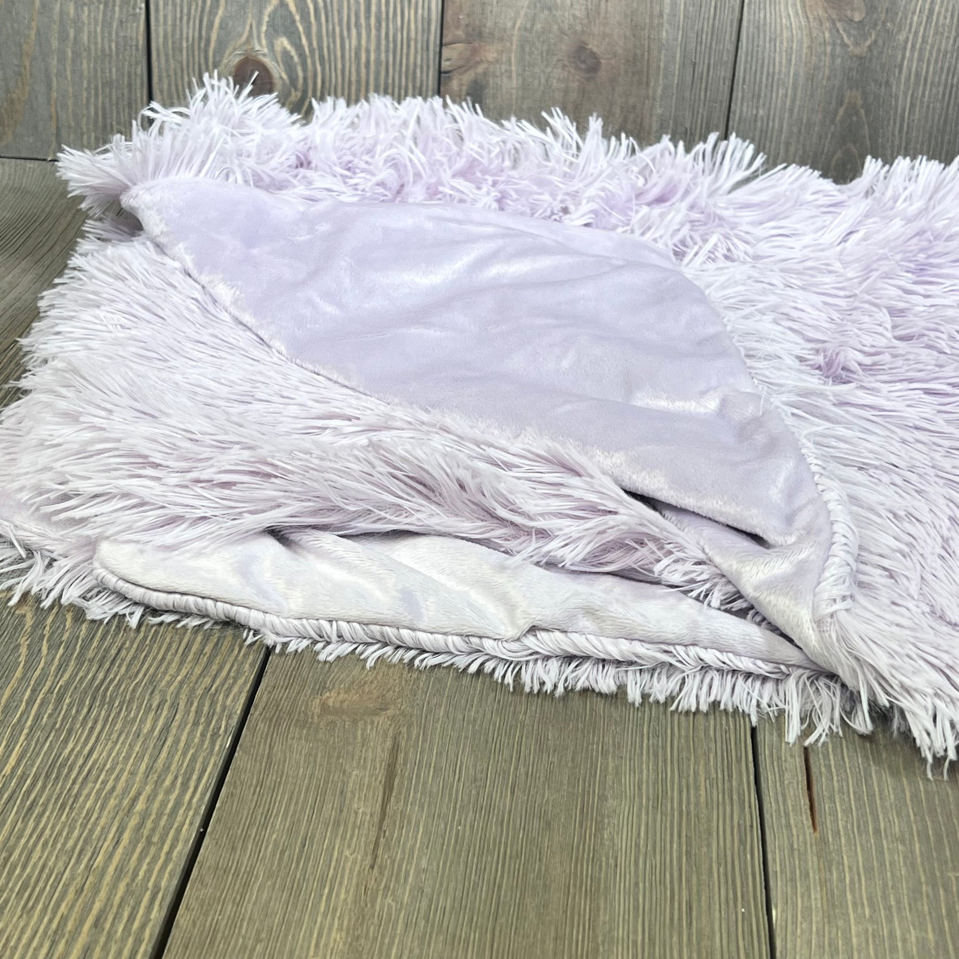 Fluffy lavender pillowcase with plush shaggy fur and velvet, showcasing zipper closure on a wooden background.