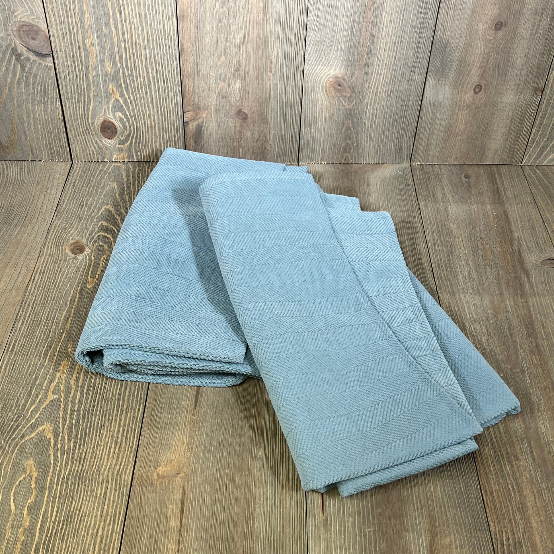 Light blue chenille pillow covers folded neatly, showcasing elegant design and soft texture, perfect for couch or bed decor.