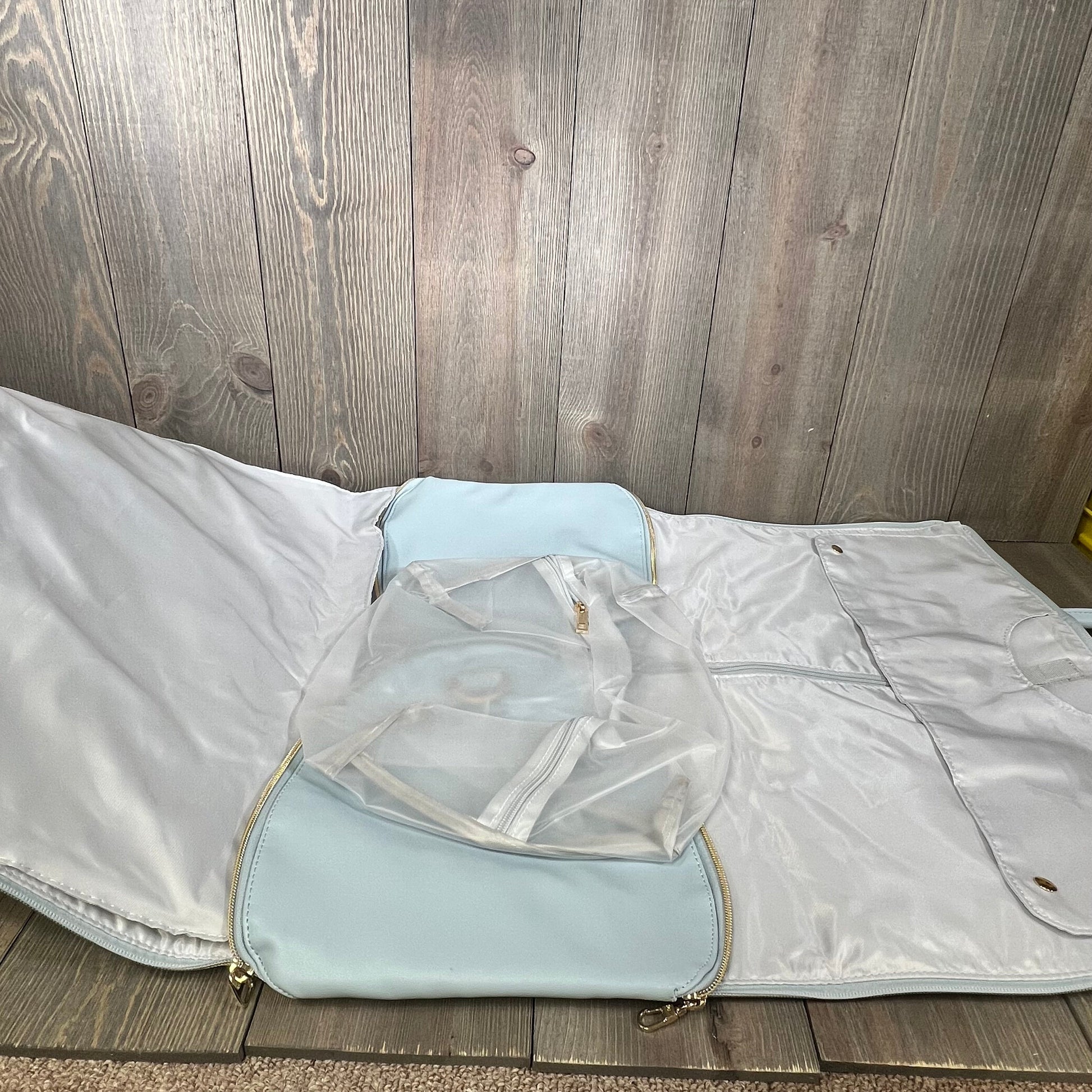 Blue PU leather garment bag open, showcasing spacious interior with toiletry pocket for organized travel.