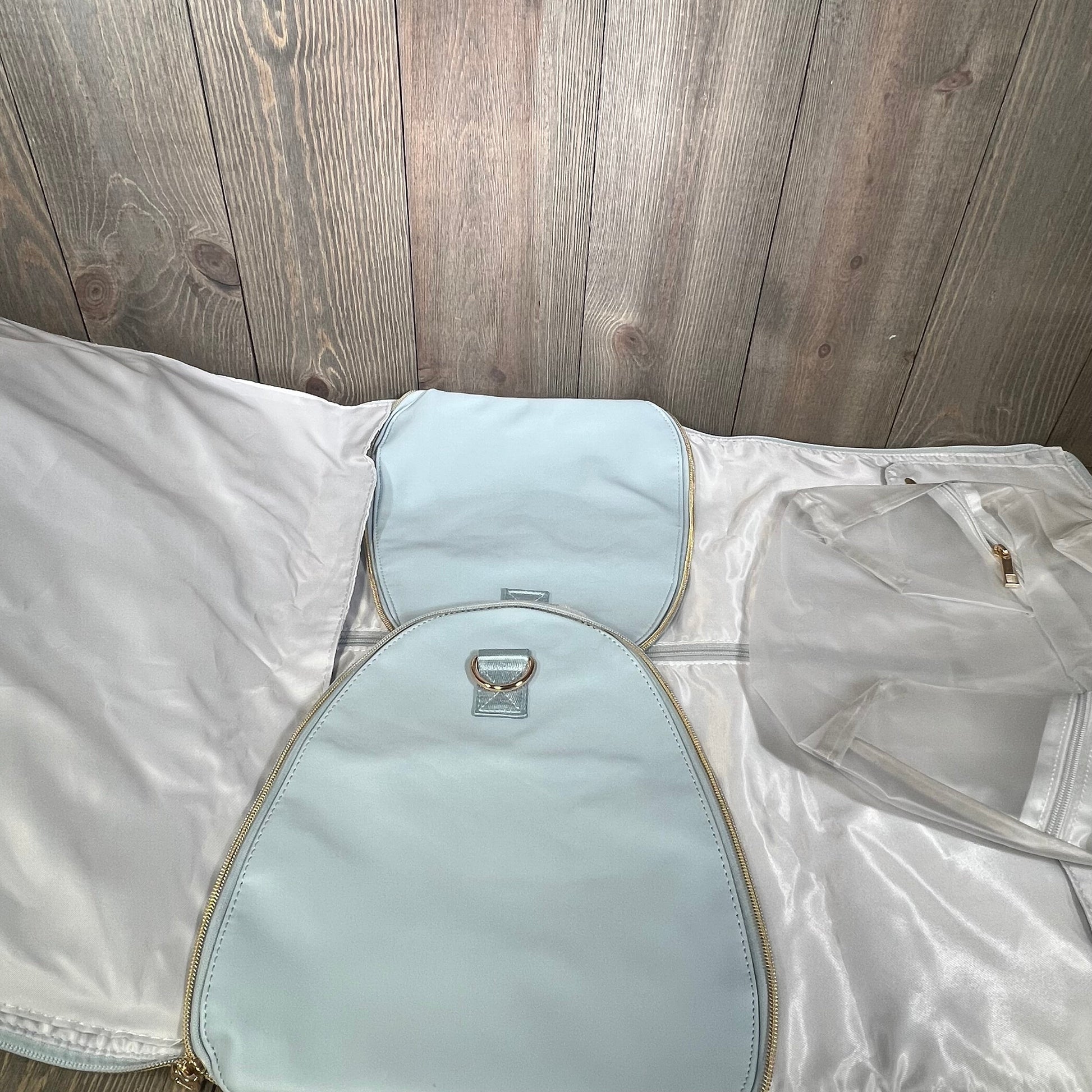 Blue convertible garment bag for women, open to reveal toiletry pocket and shoe compartment, perfect for stylish travel.