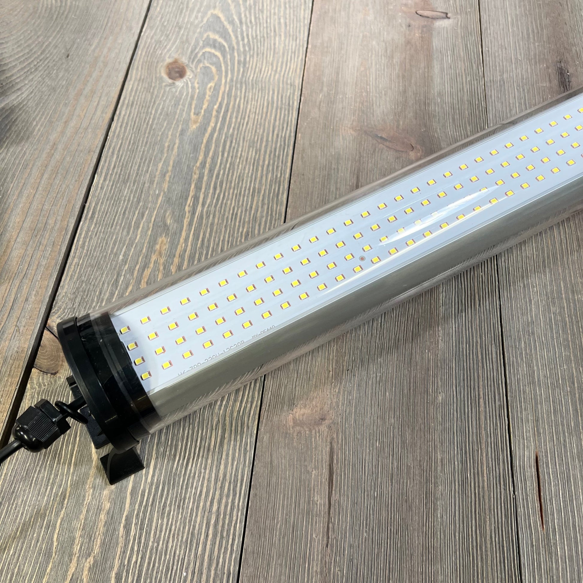 Explosion-proof LED machine light tube on wooden surface, ideal for CNC industrial lighting, 25W, IP66, 110V-220V.