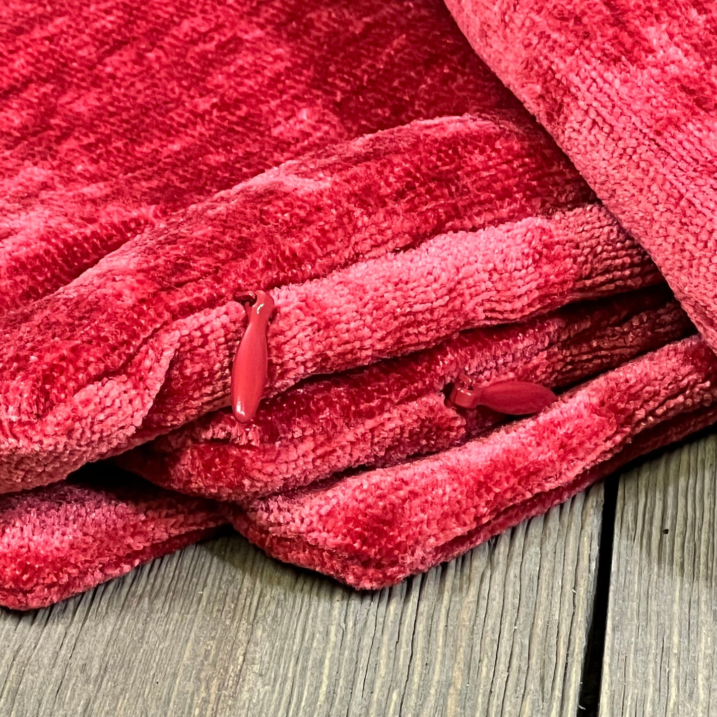 Bright red chenille throw pillow covers stacked on a rustic wooden floor, showcasing soft texture and vibrant color.