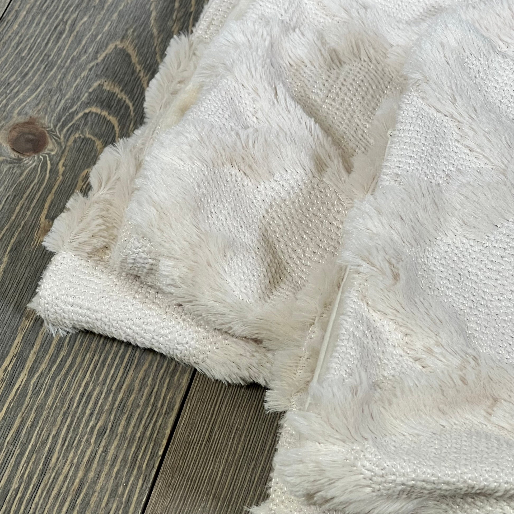 Fluffy beige Moroccan pillow covers on rustic wood floor, showcasing soft texture and boho design for couch or bed.