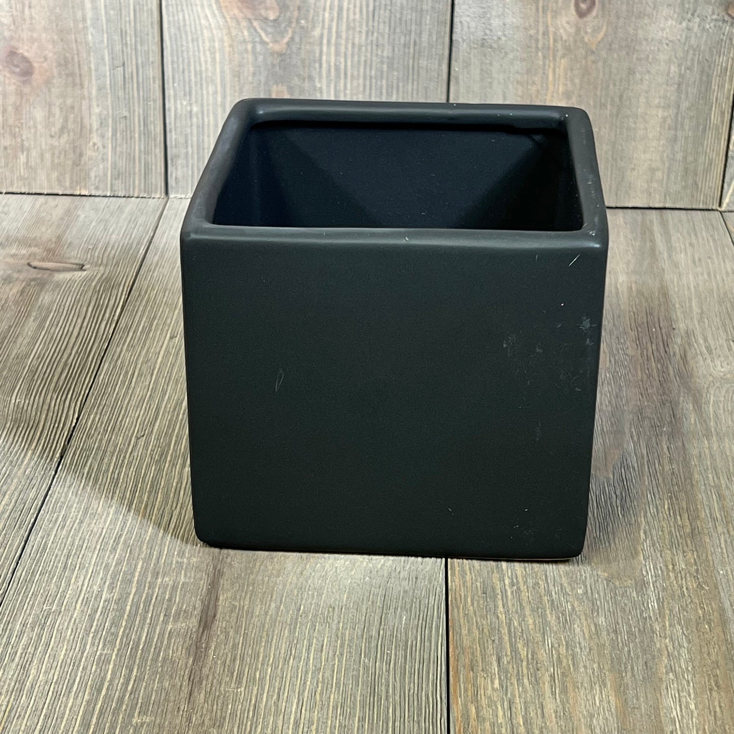 Modern black ceramic square plant pot on wooden surface, perfect for small plants and succulents, stylish and decorative.