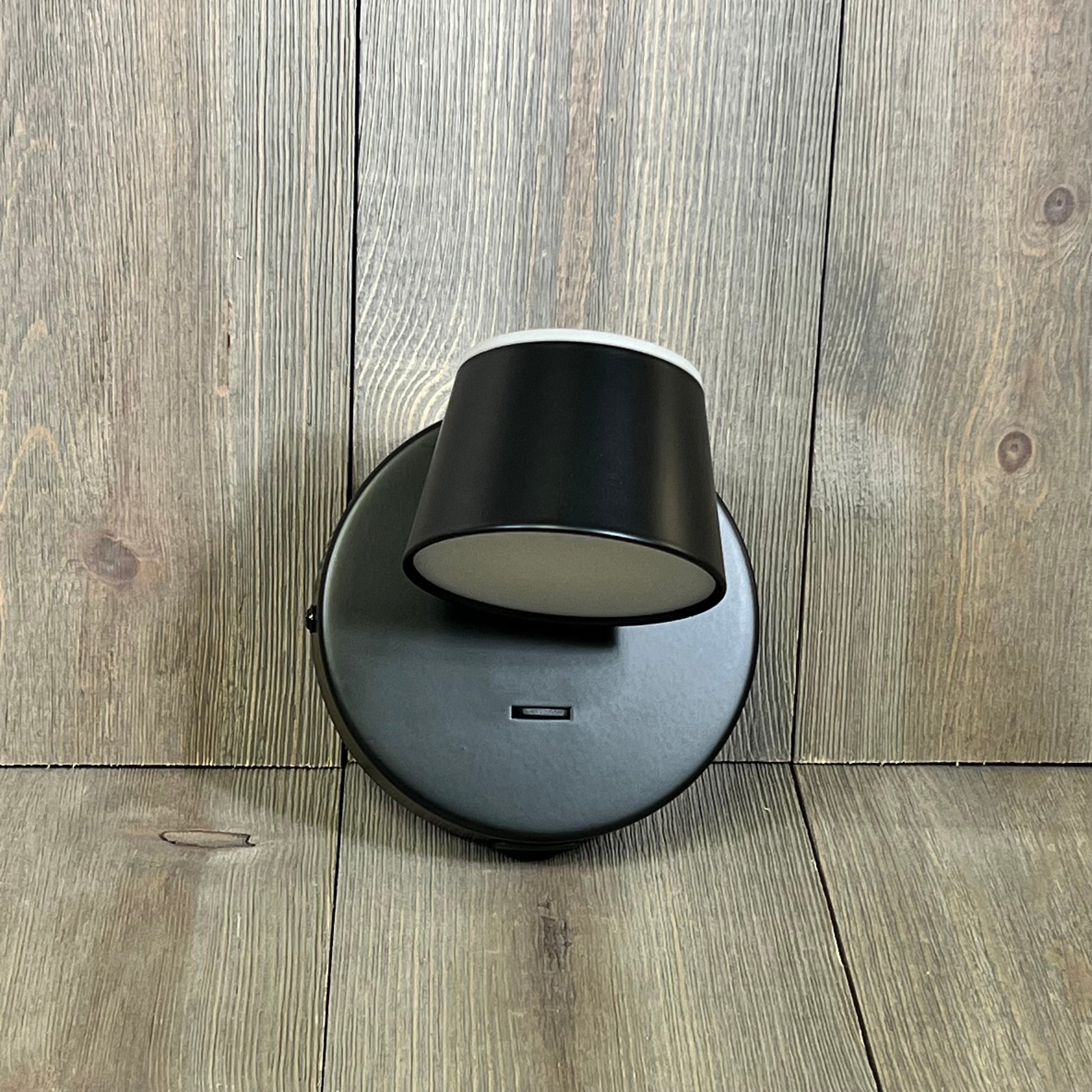 Black URSOLA LED wall sconce with rotatable head, USB port, and on/off switch, mounted on a wood-textured background.